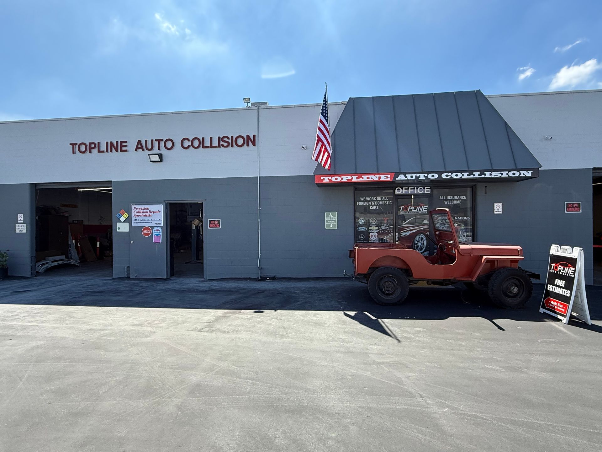 Topline Auto Collision shop with an orange Jeep and American flag on a sunny day.
