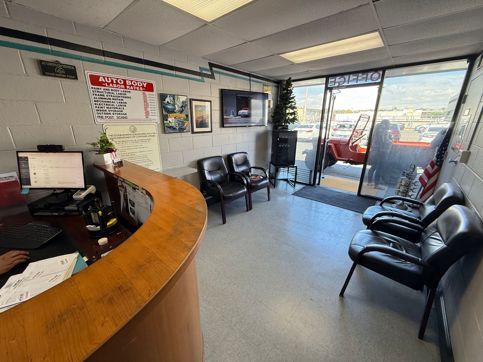 Reception area with curved wooden desk, black chairs, and a view of outside.