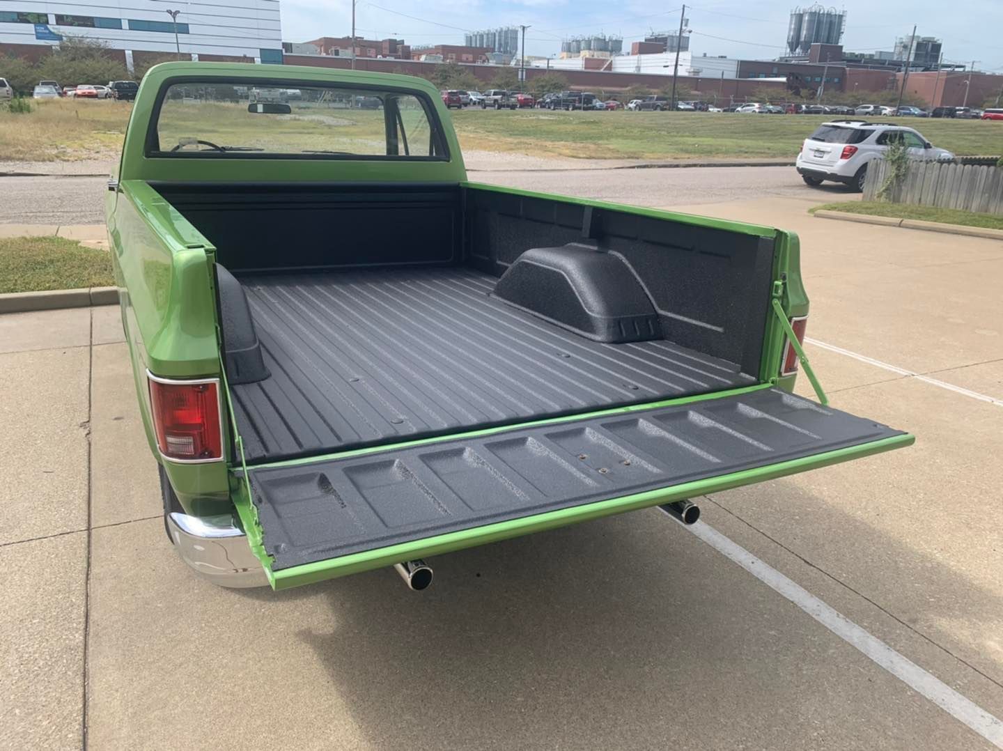 Green classic pickup truck with an open bed in a parking lot.