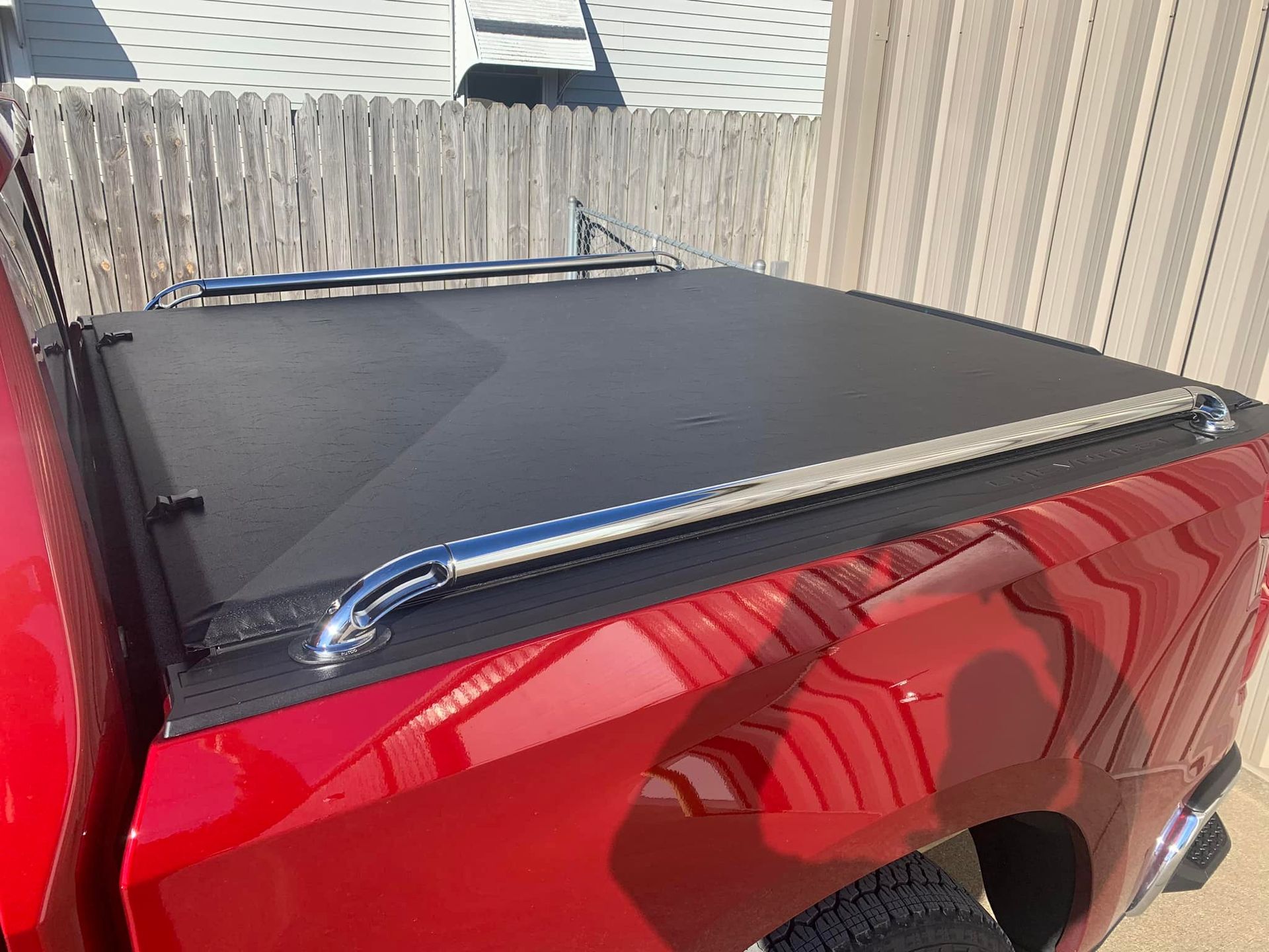 Red pickup truck with a black tonneau cover and chrome bars.
