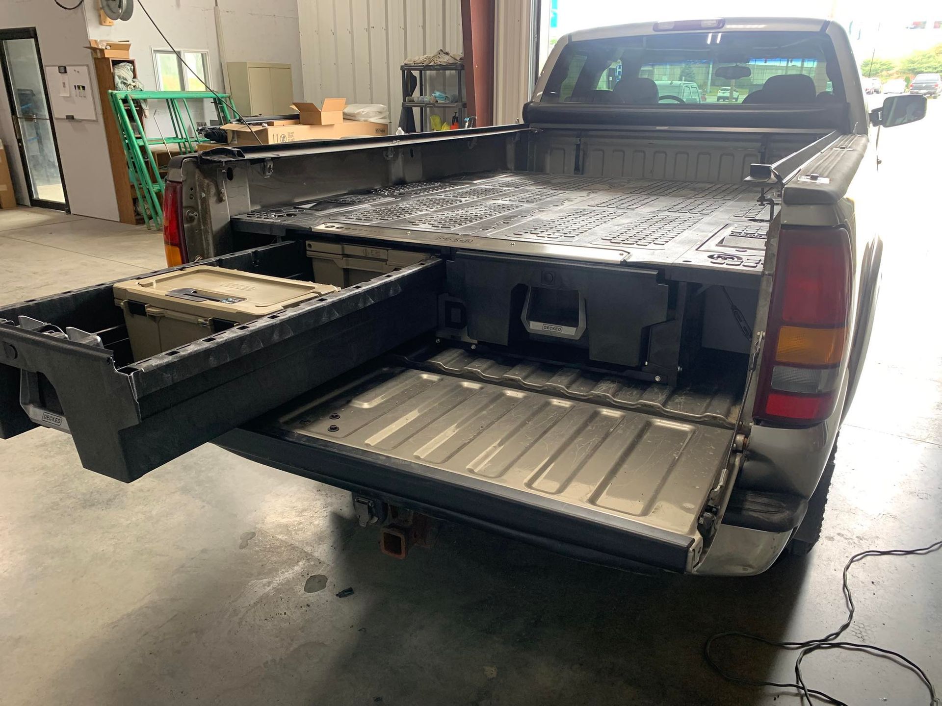 Truck bed with a slide-out cargo system, gray truck, open on a concrete floor.