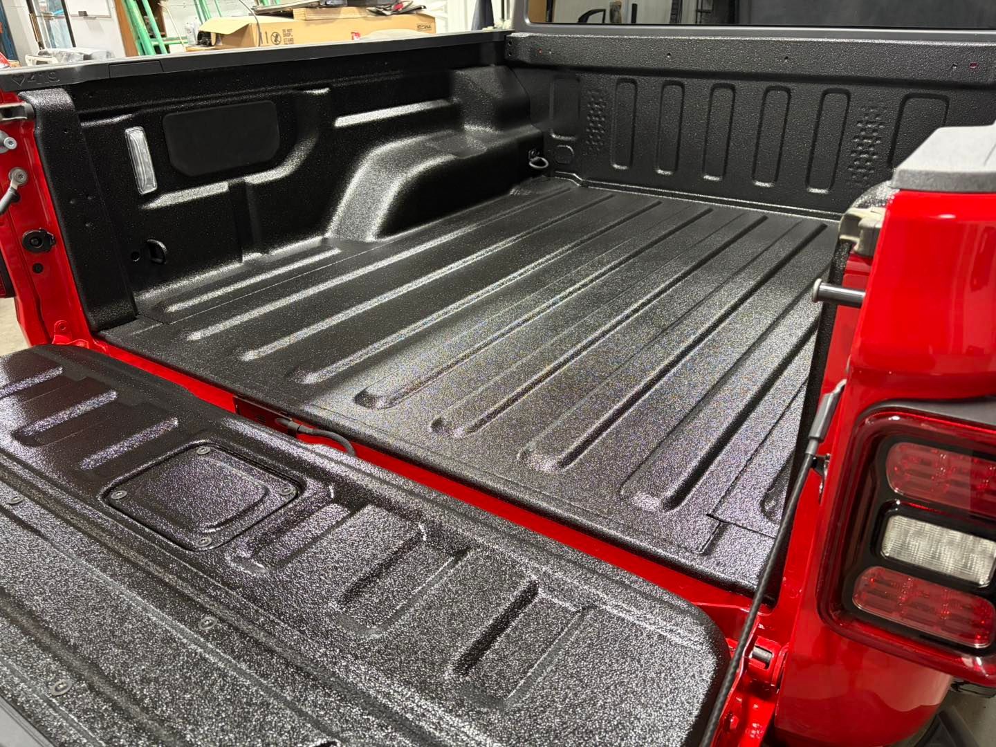 Black bed liner in a red pickup truck bed.