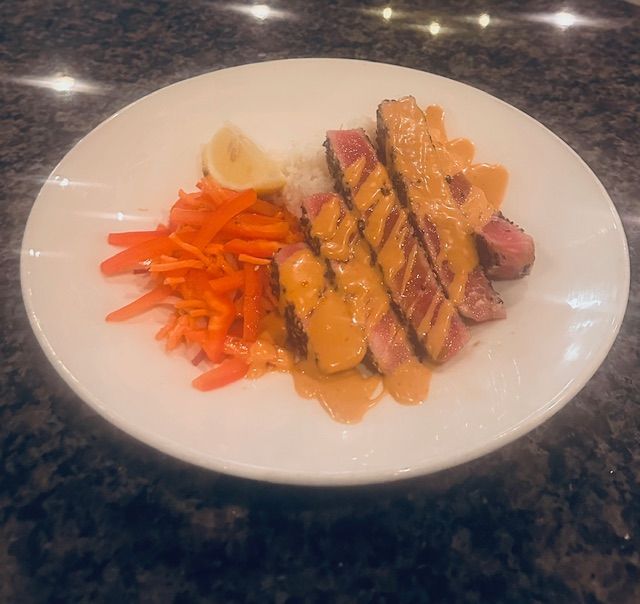 Plated steak with sauce, roasted potatoes, and sliced carrots on a white plate