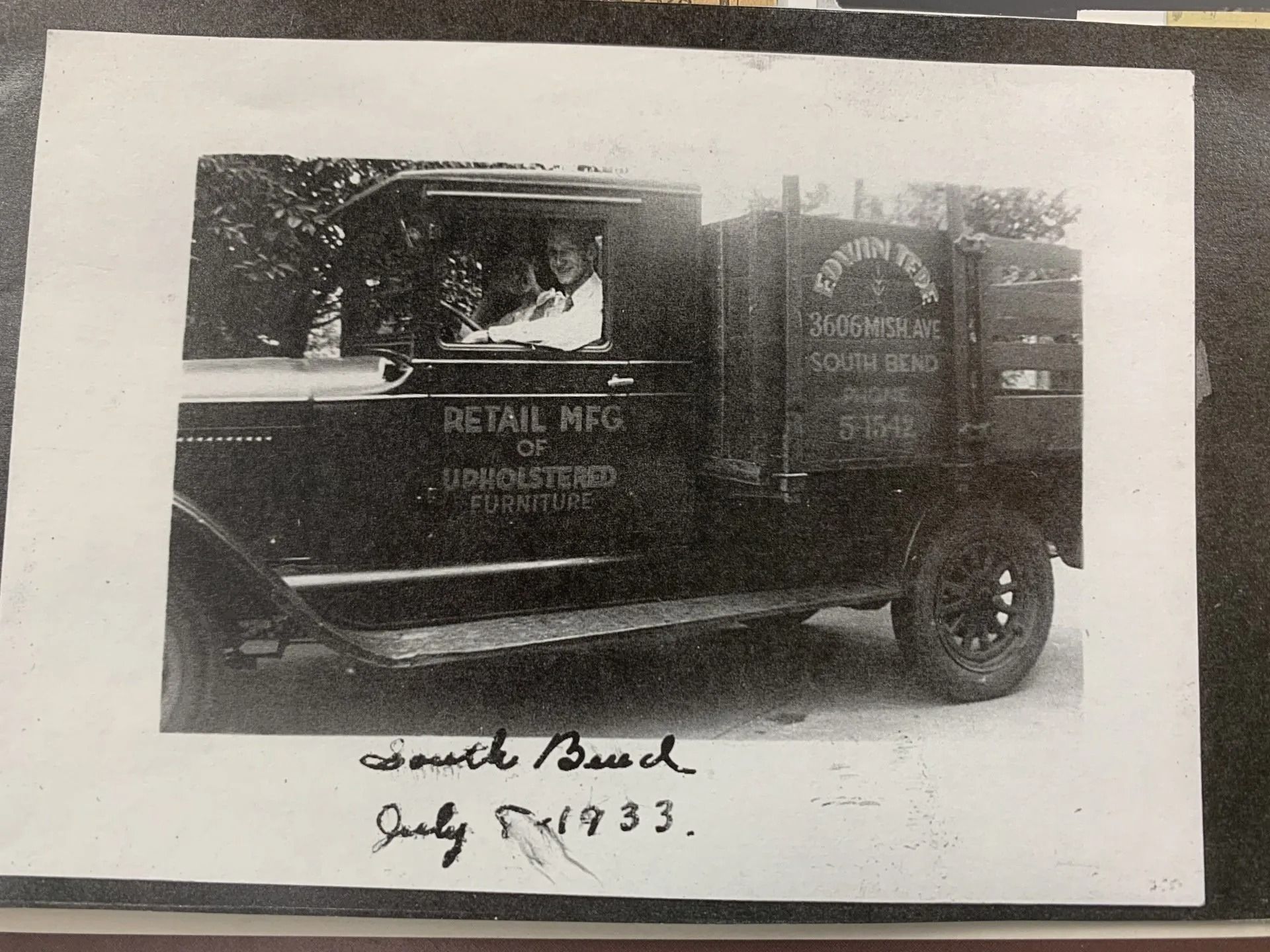 Vintage delivery truck with signs, photographed in black and white.
