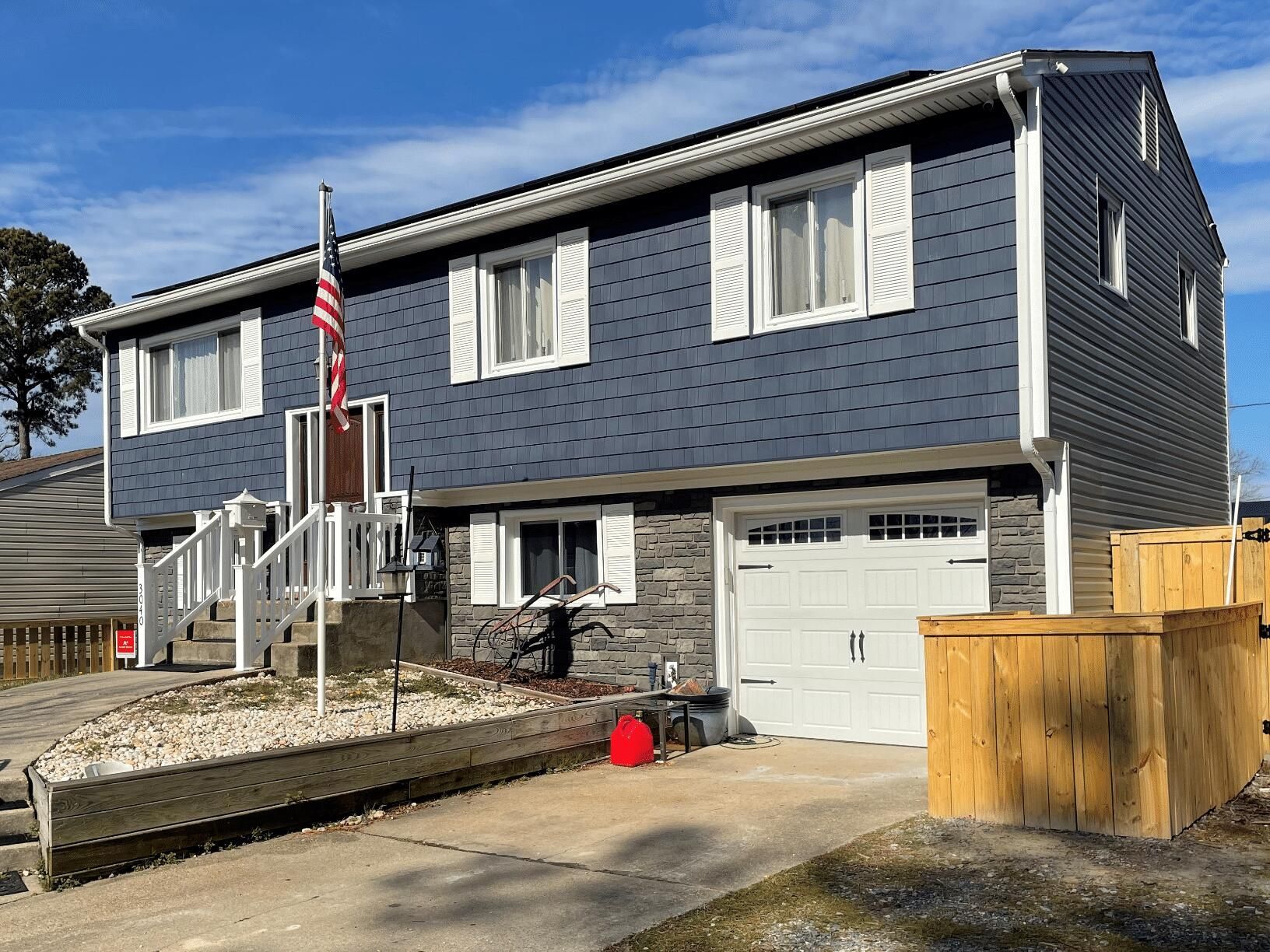 A large house with a blue siding and white shutters is for sale.
