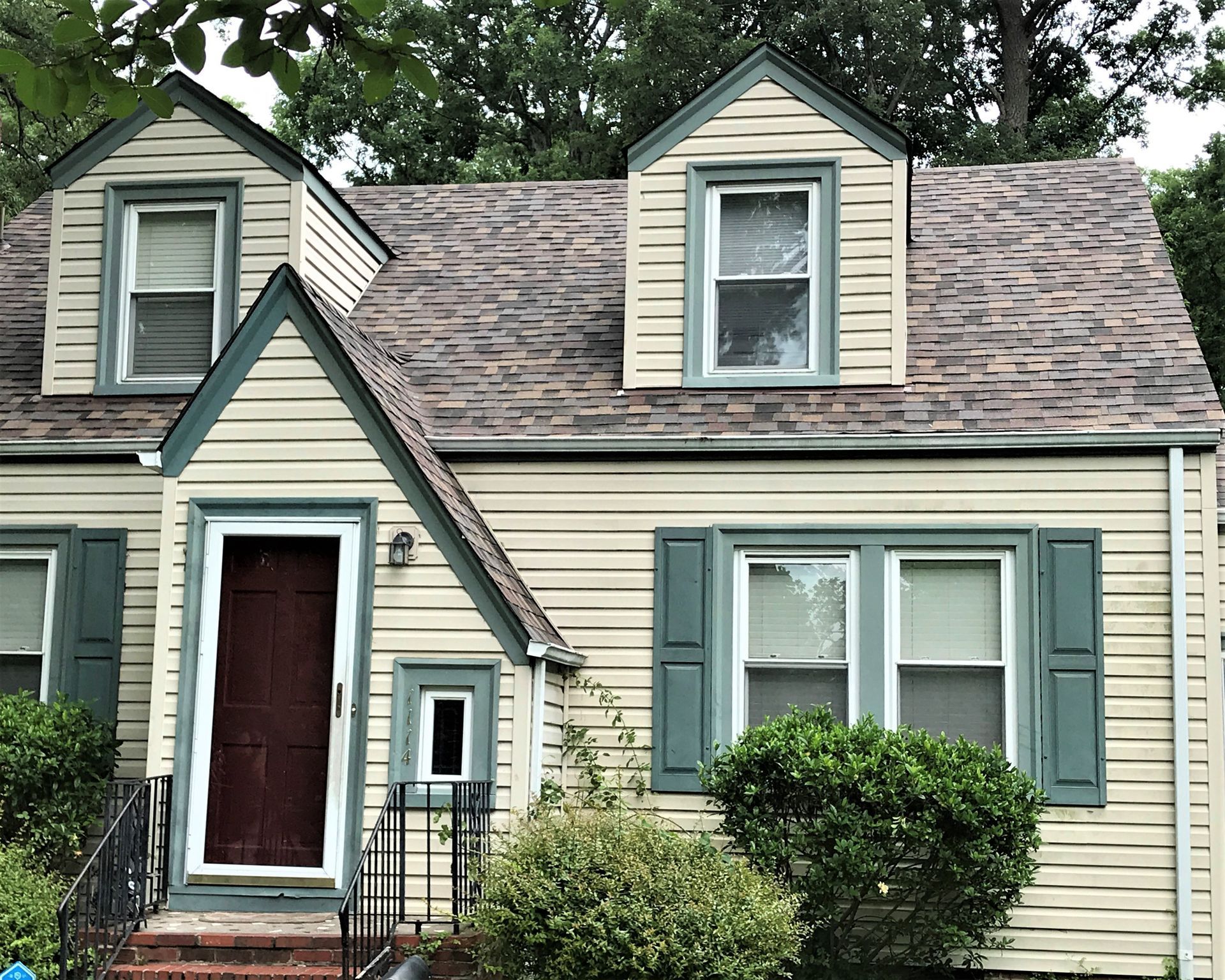 A house with a brown roof and green shutters.
