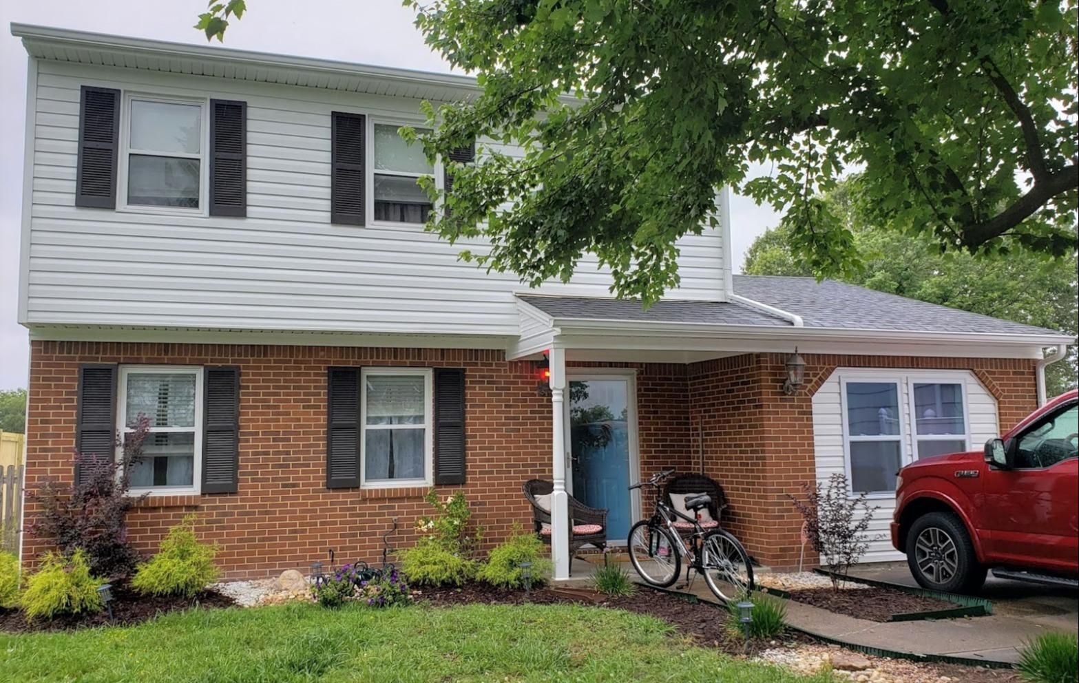 A red truck is parked in front of a brick house.