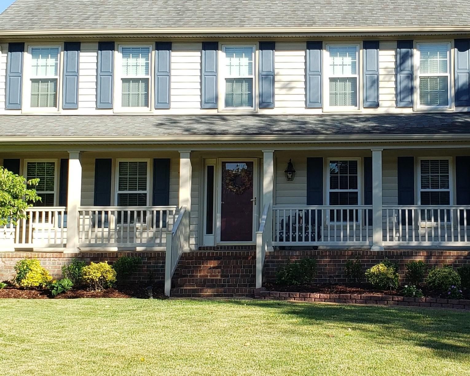A large white house with black shutters and a large porch