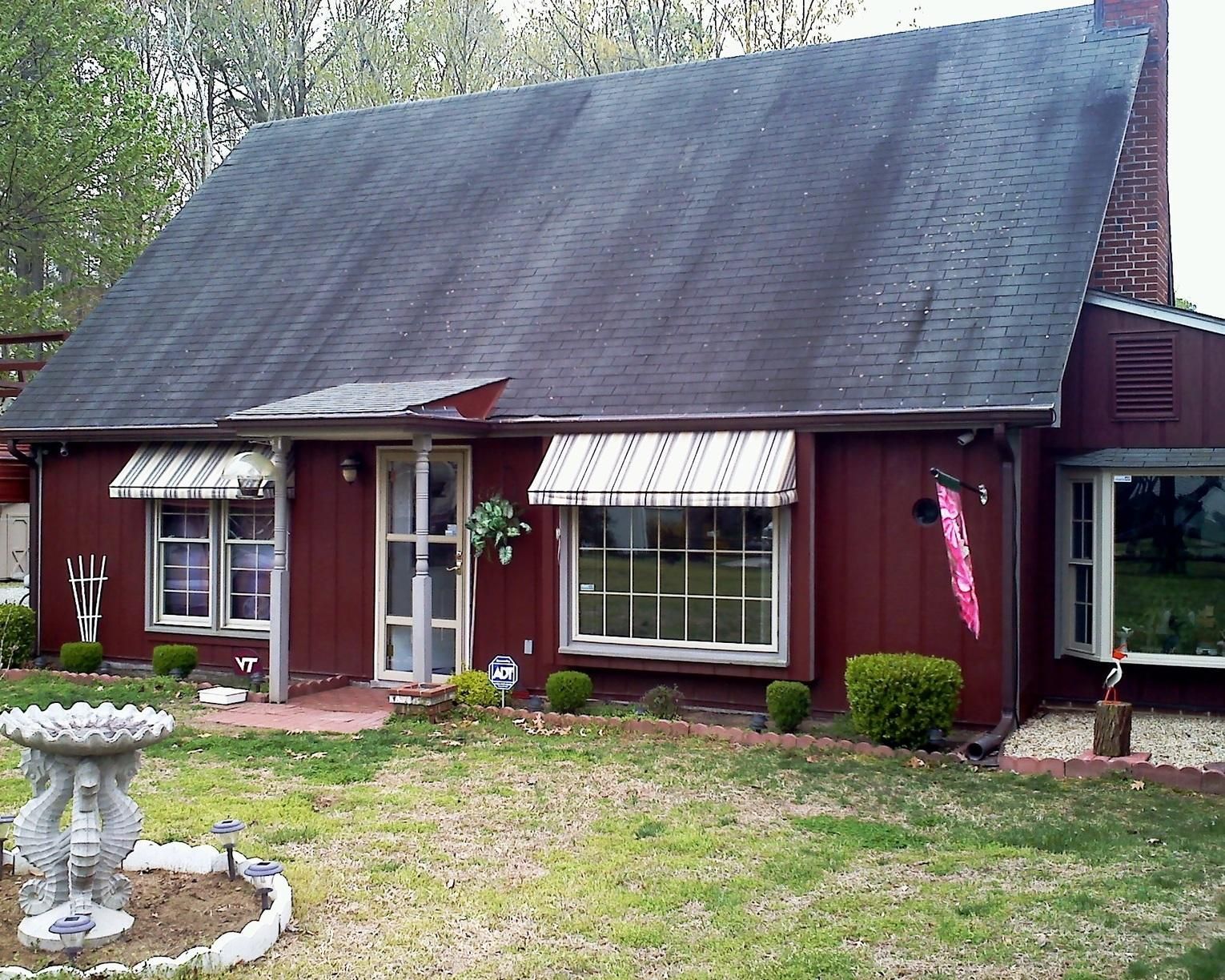 A red house with a black roof and white awnings