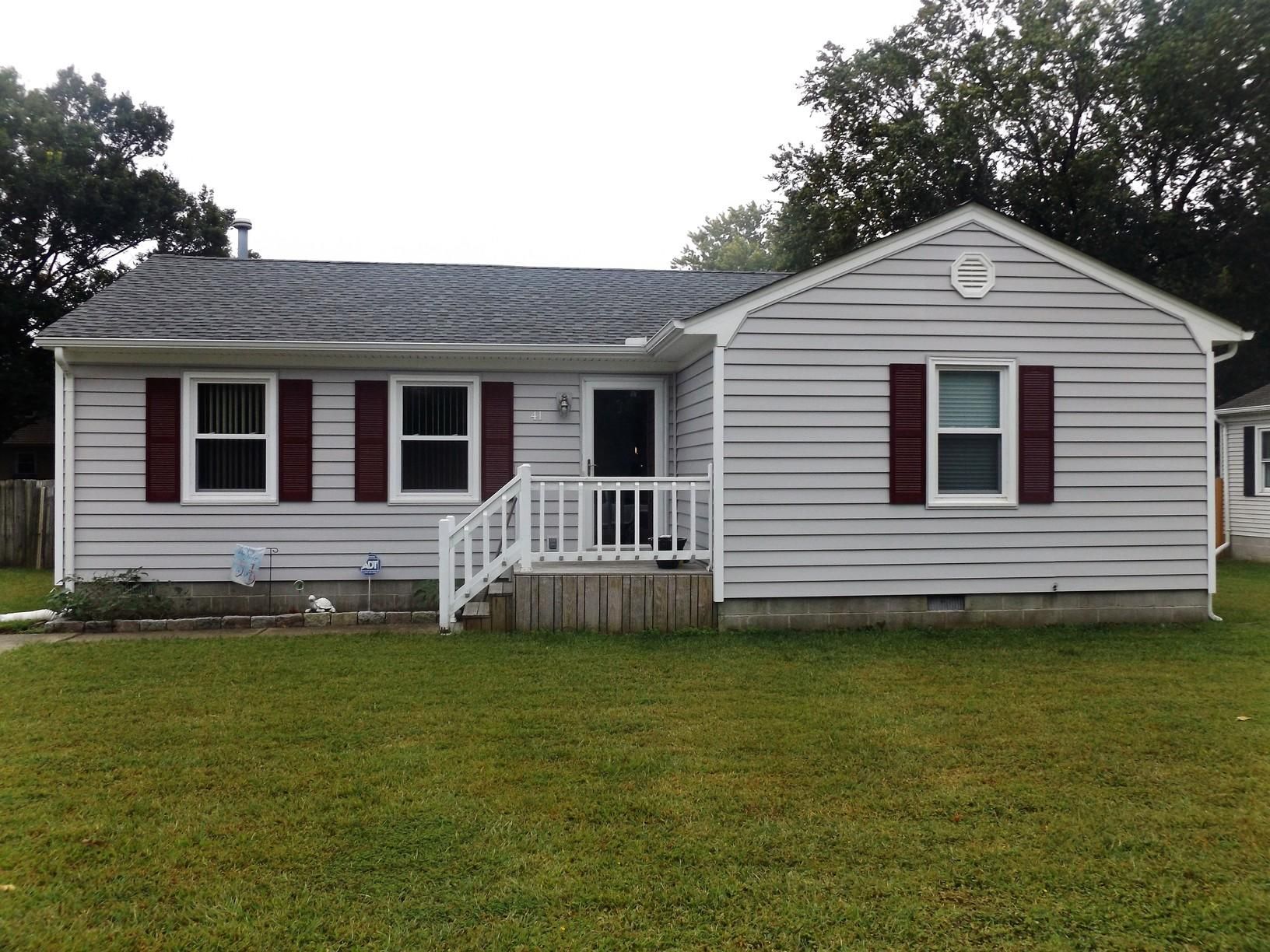 A white house with red shutters and a white porch