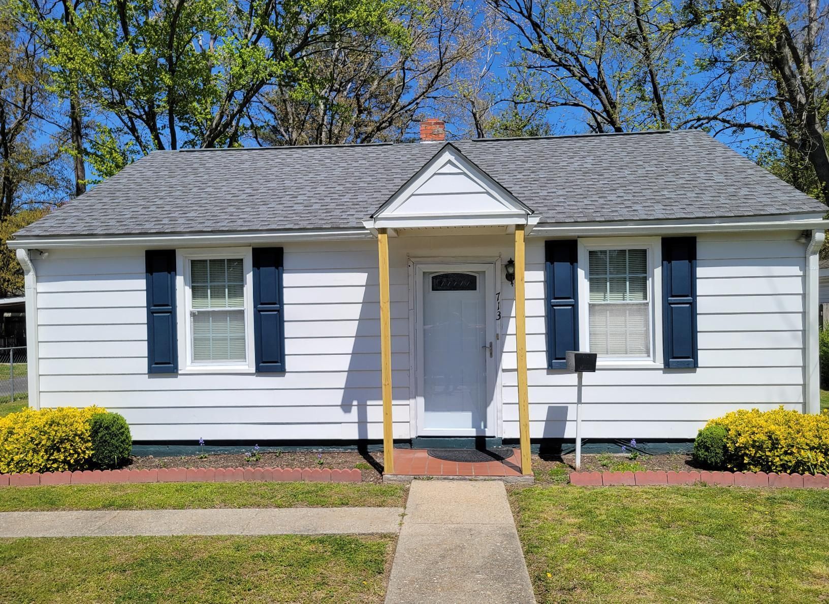 A small white house with blue shutters and a gray roof.