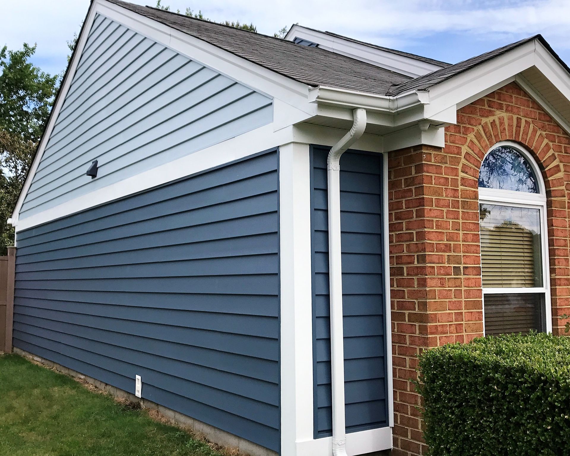 A brick house with a blue siding and white trim.