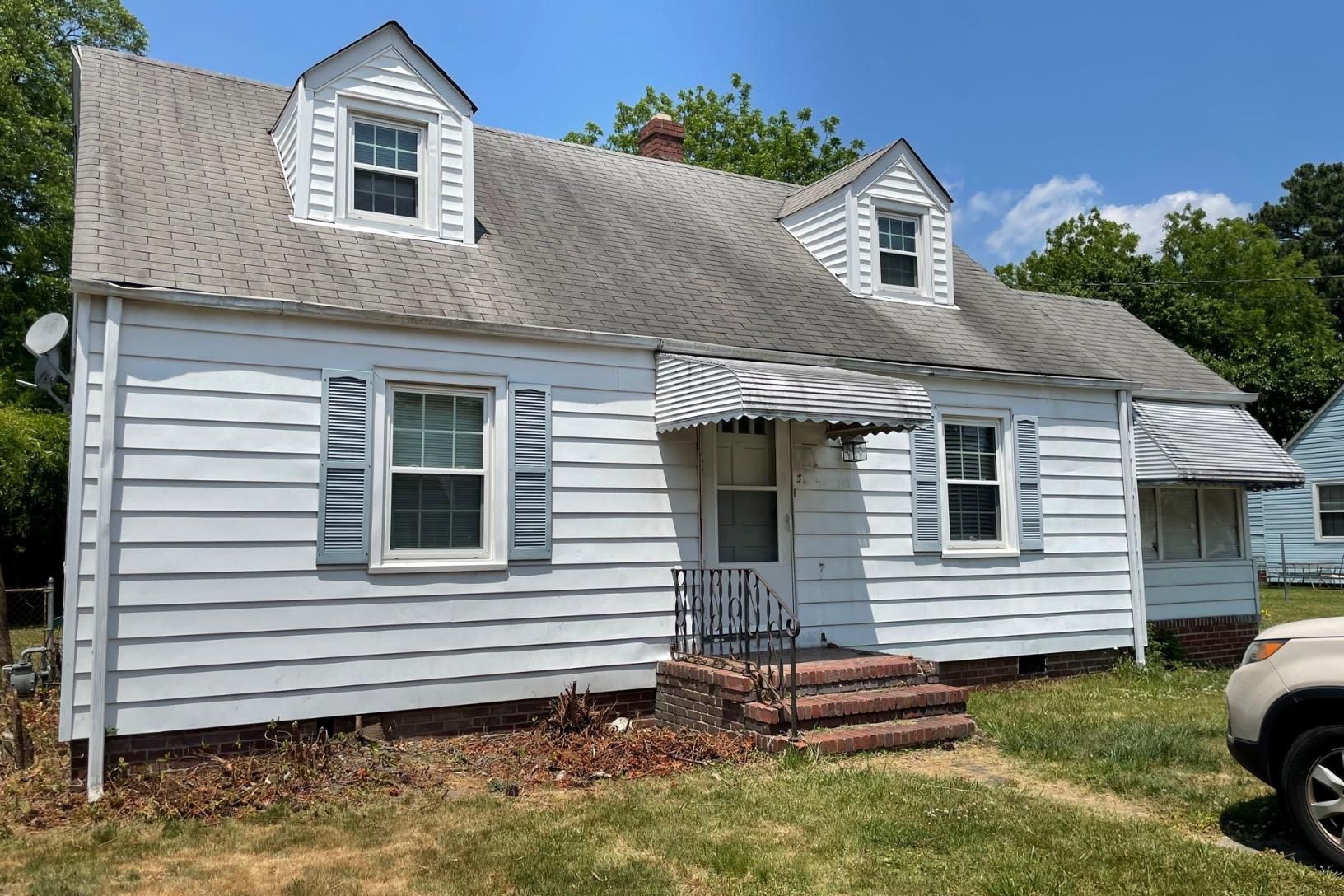 A white house with a car parked in front of it.