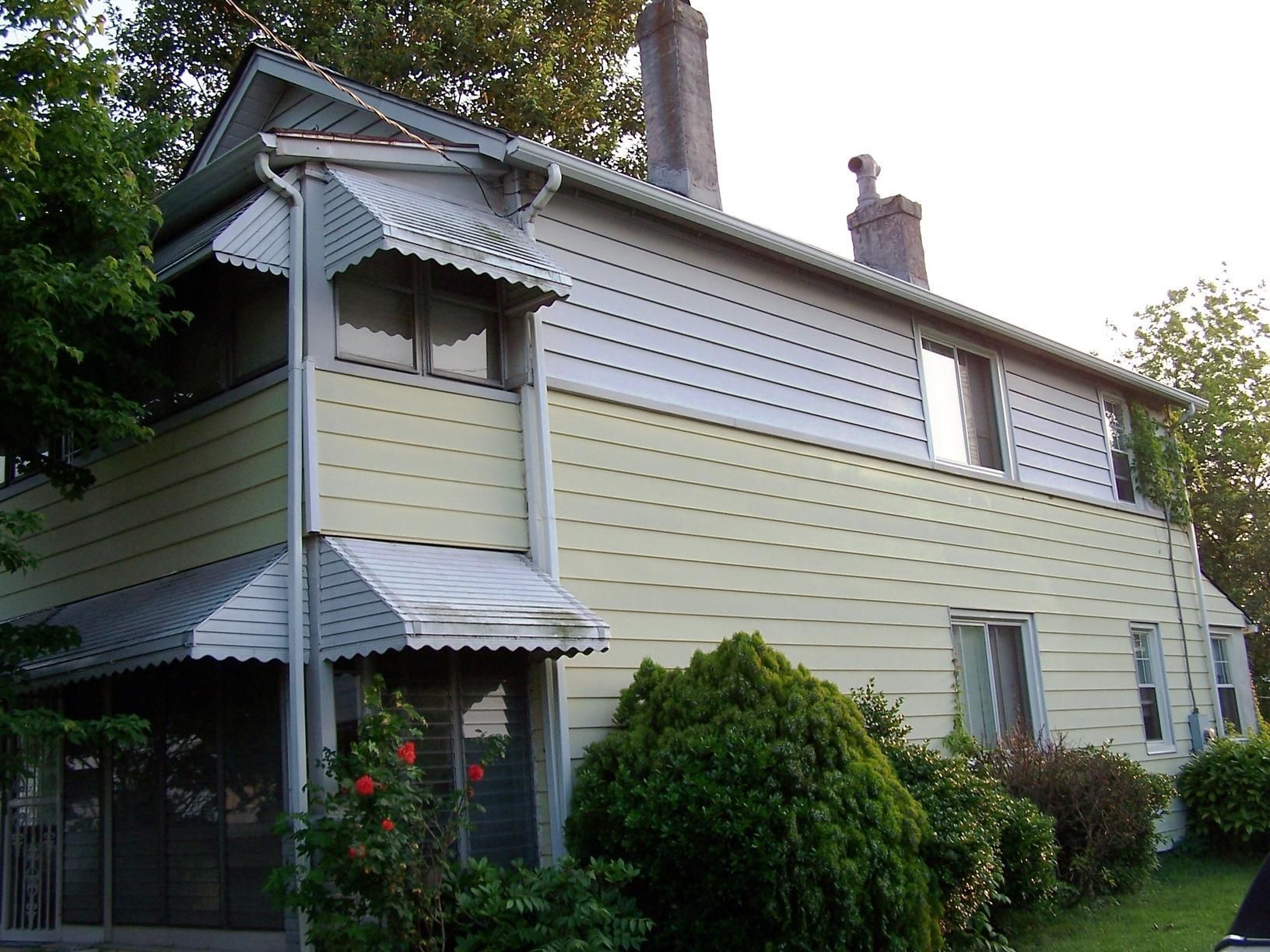 A yellow house with a white awning on the porch