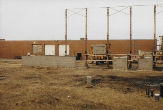 Brown brick building with three white doors, outdoor construction site.