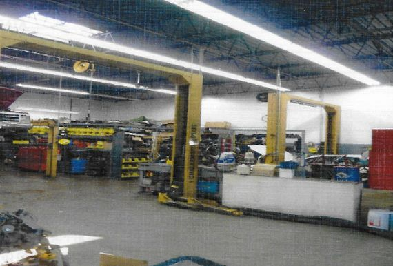 A car repair shop interior with vehicle lifts, tools, and equipment. Bright overhead lights.
