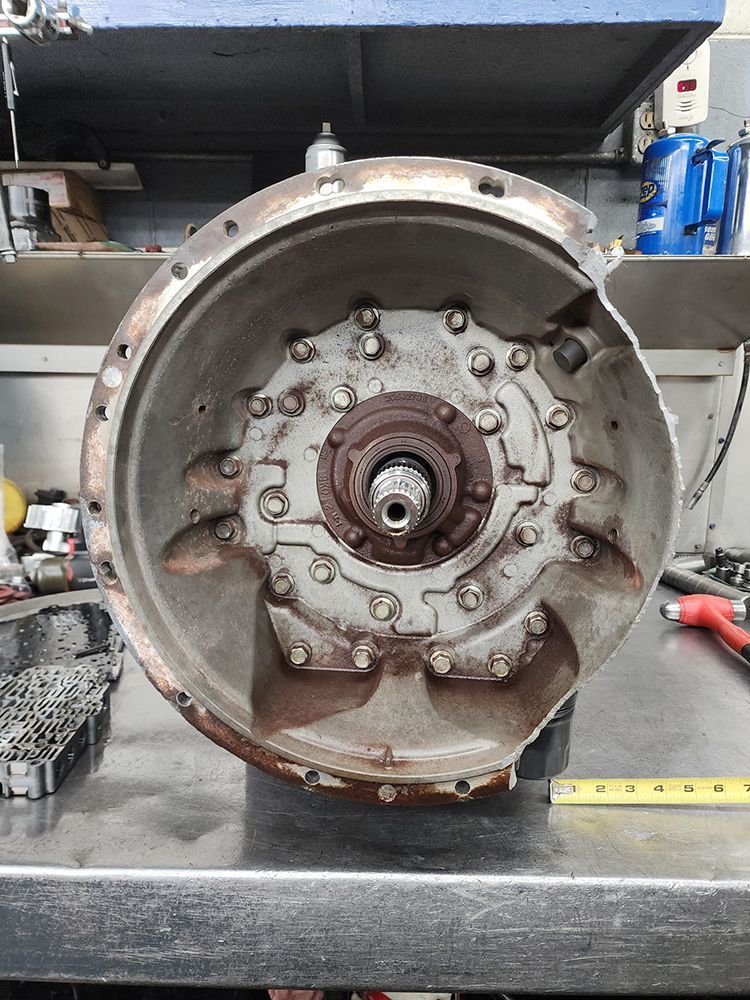 Open transmission casing, showing internal gears and shaft, on a work surface.