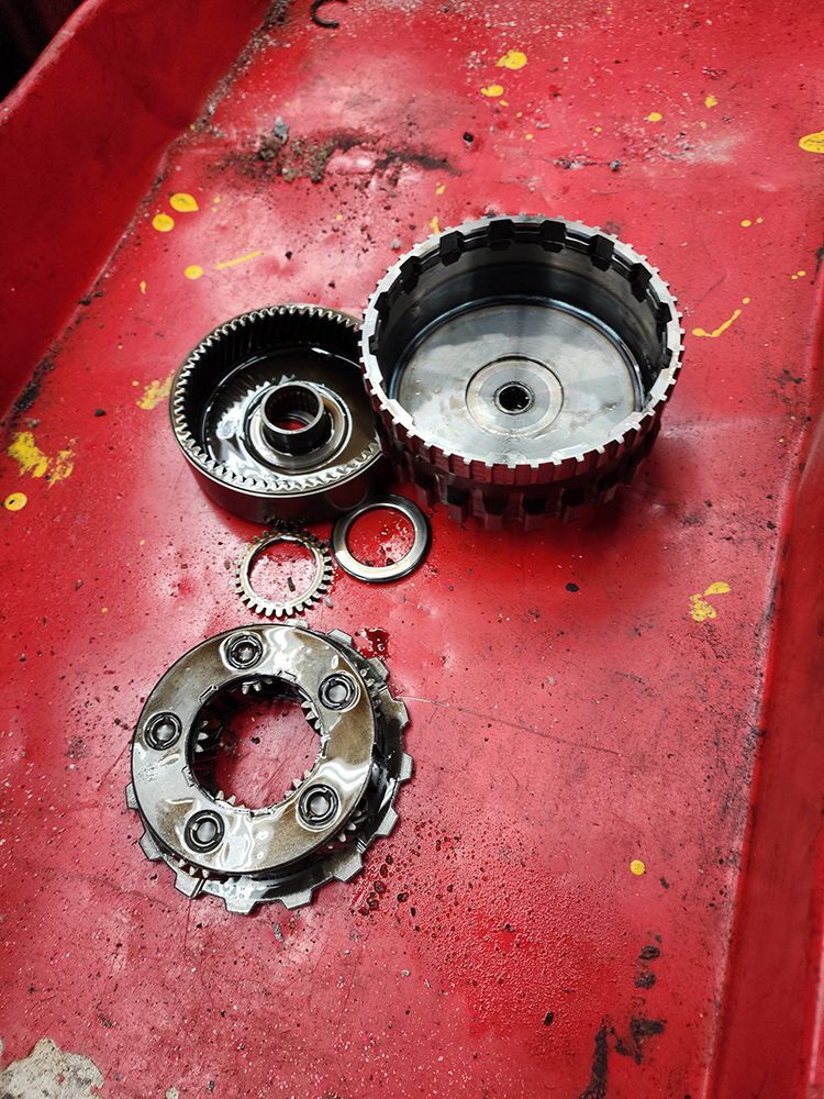 Disassembled automotive transmission parts on a red tray.