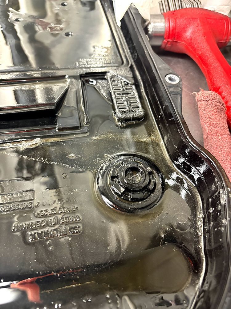 Black plastic automotive part with a circular opening and debris.