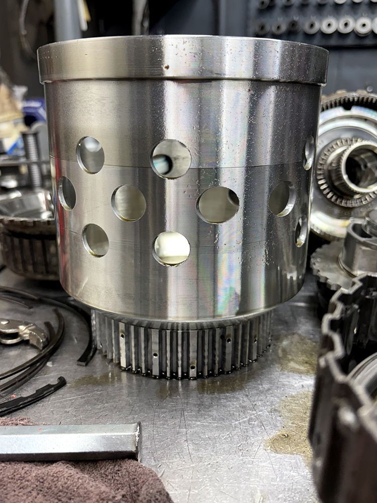 Metal transmission component with circular holes, on a workbench.