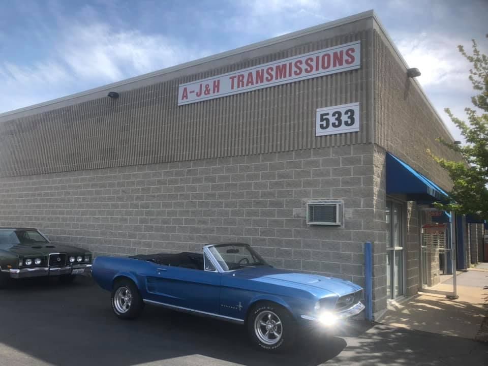 Blue convertible parked outside A-&H Transmissions building with sign at 533.