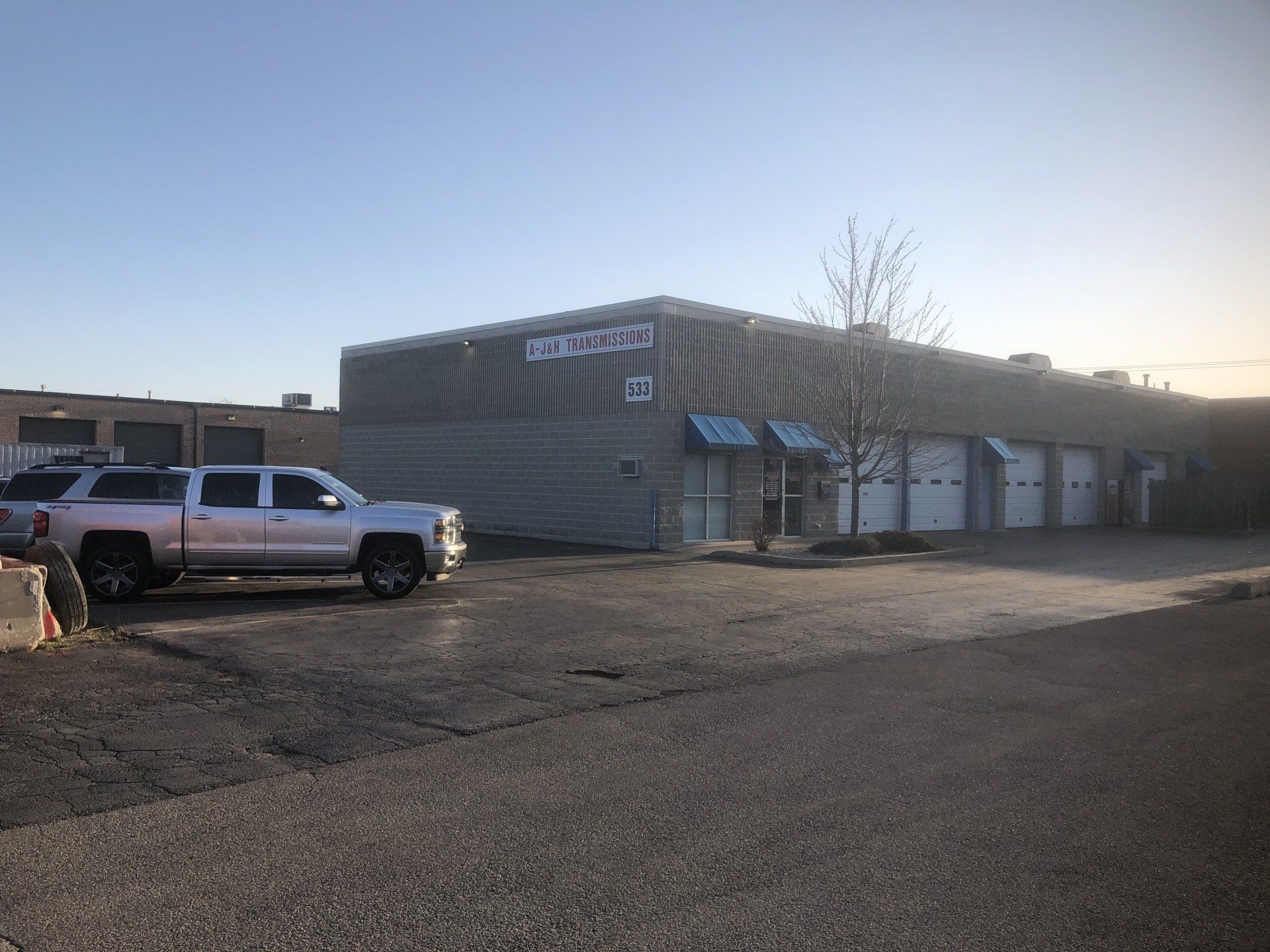 A commercial building with a sign and multiple garage doors; a silver SUV is parked out front.