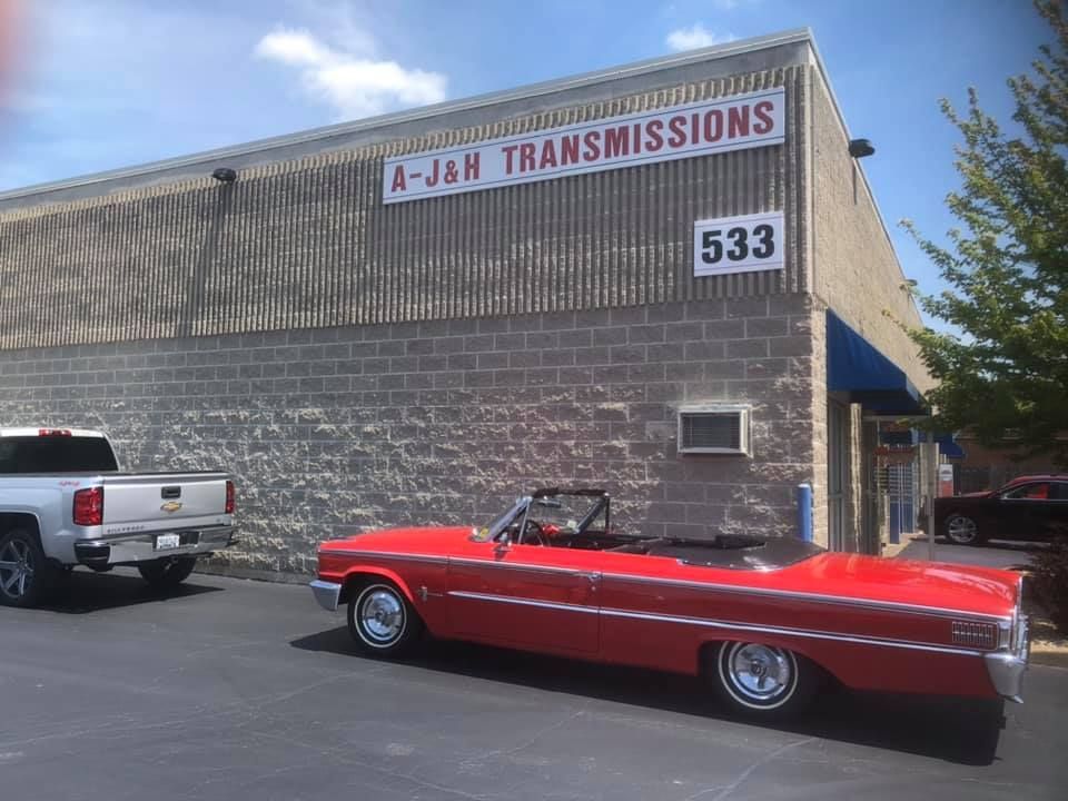 Red convertible parked outside A-&J Transmissions shop at 533. A pickup truck is next to the car.