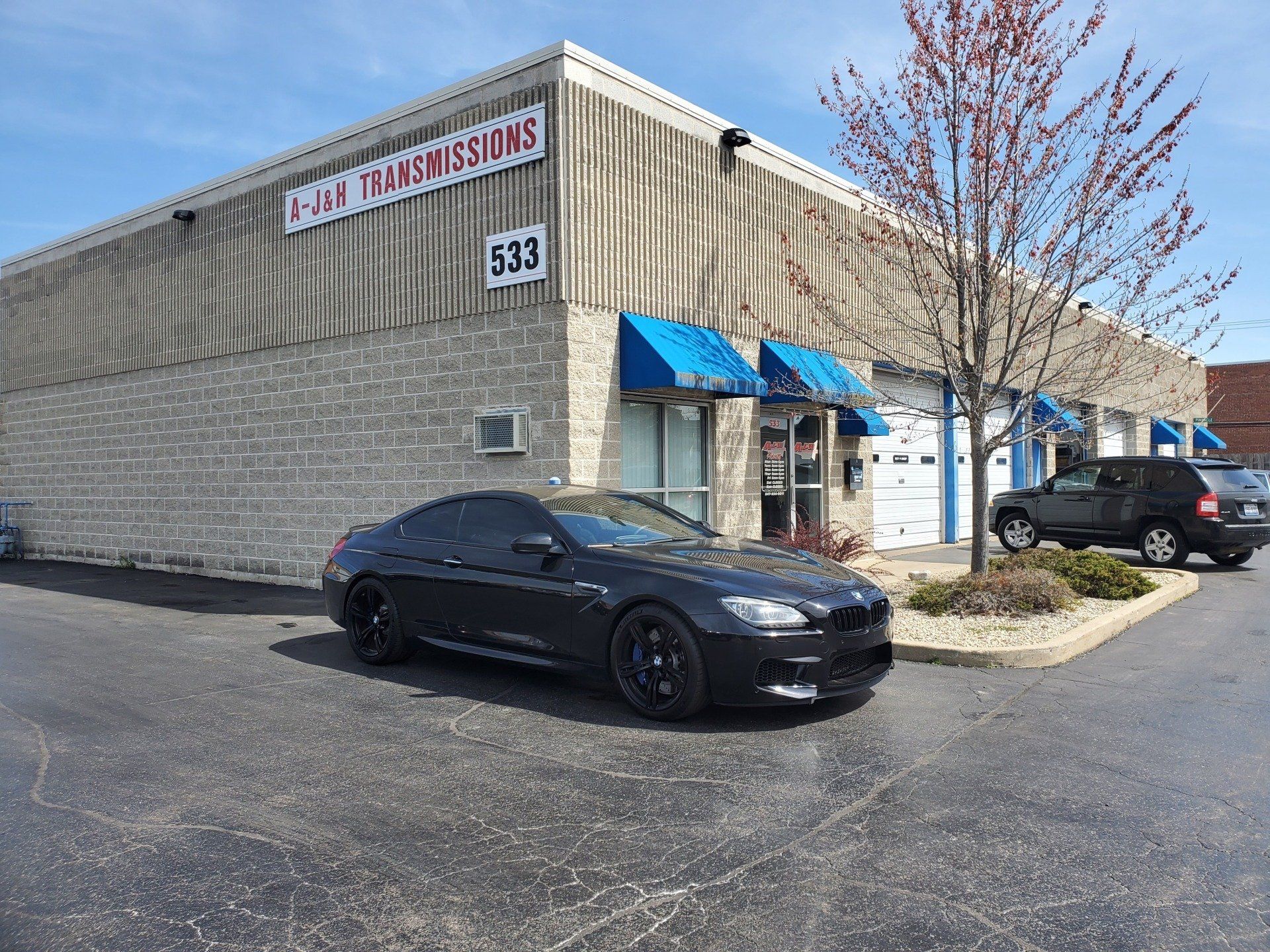 Dark gray car parked in front of a building labeled 