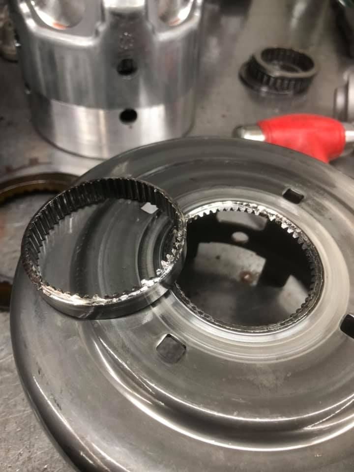 Close-up of a damaged metal gear ring next to a larger circular metal part.