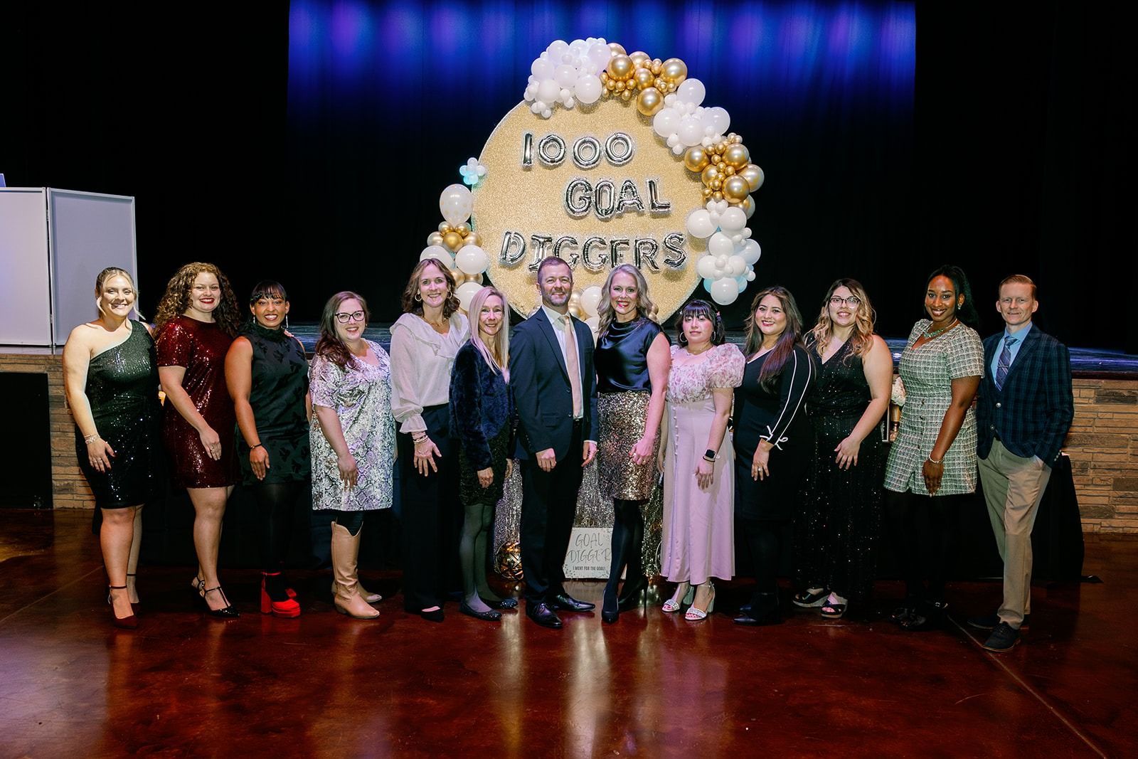 Group of people pose in front of a sign that reads 