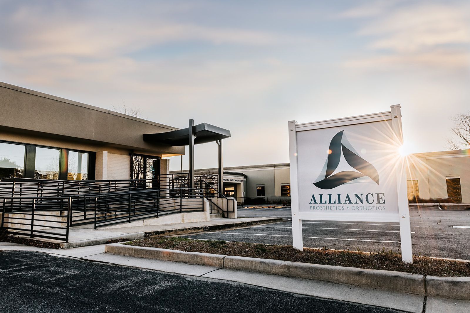 Sign for Alliance Commercial Real Estate in front of a modern building, with a sunset in the background.