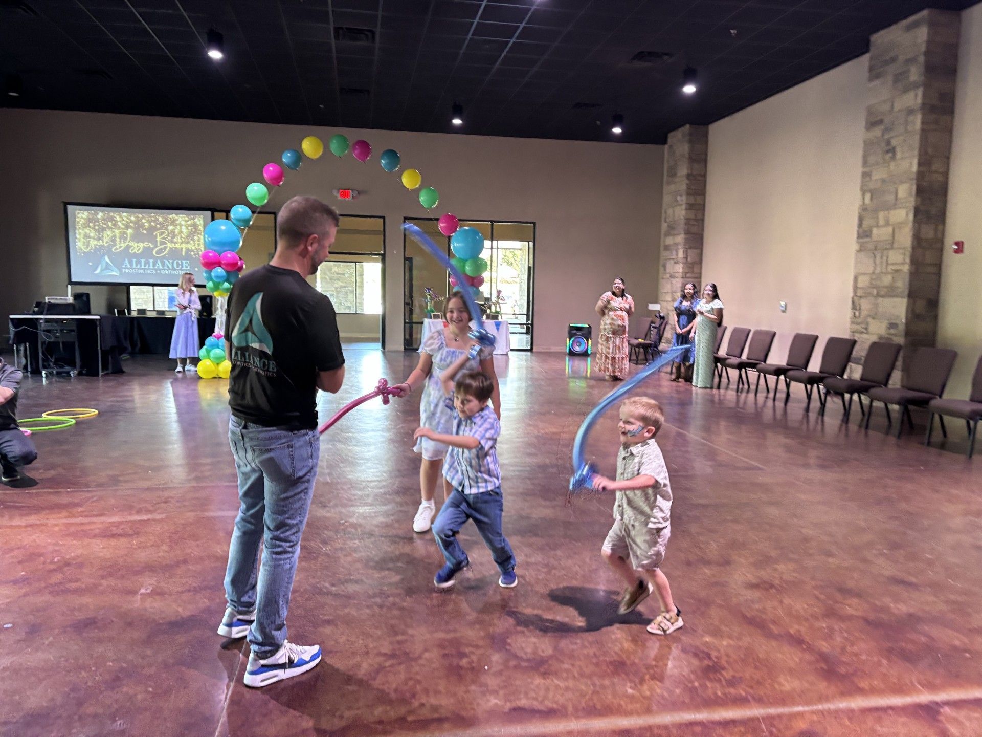 Children playing with balloon hoops in a spacious hall decorated with a colorful balloon arch