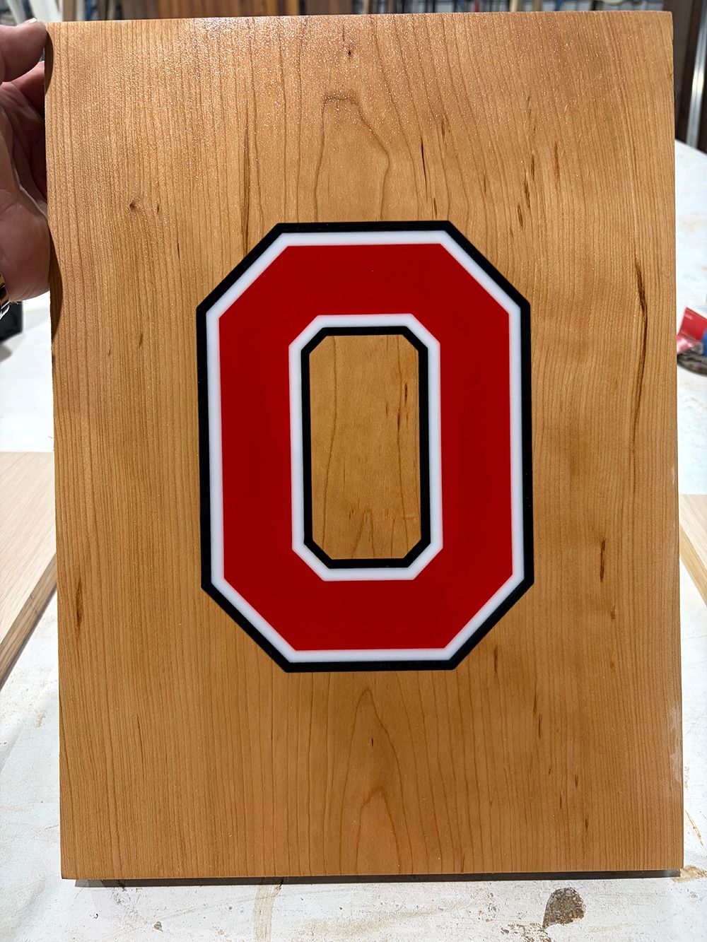 Red and white block letter “O” on a wooden plaque.