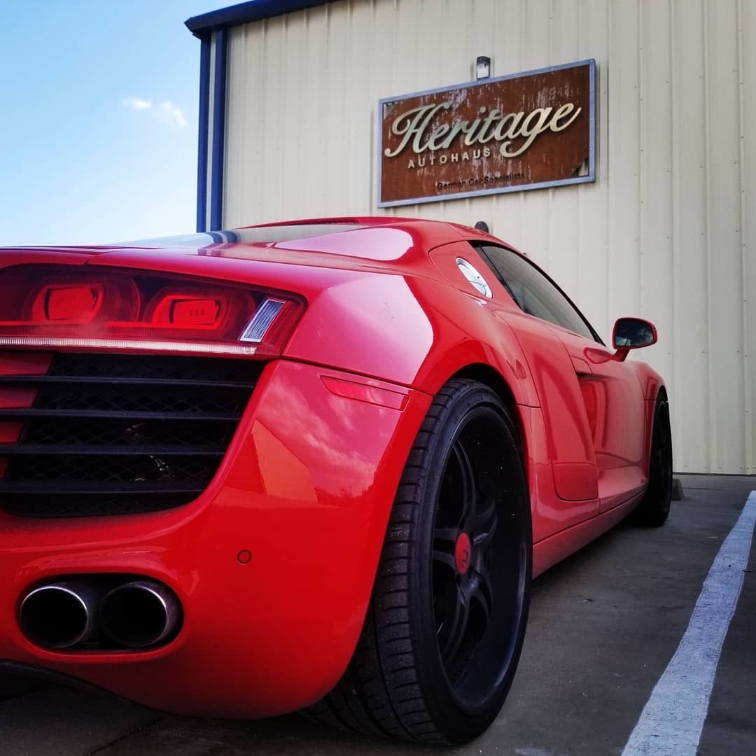 Red sports car parked beside a building with a Heritage sign.
