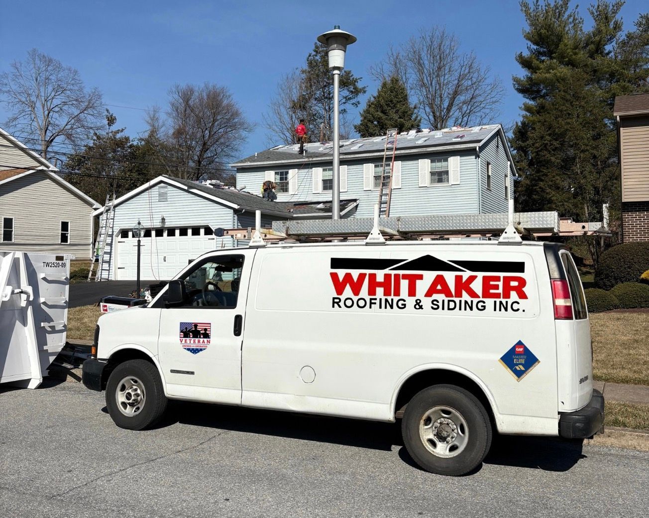 A white van from whittaker roofing and siding inc. is parked in front of a house.