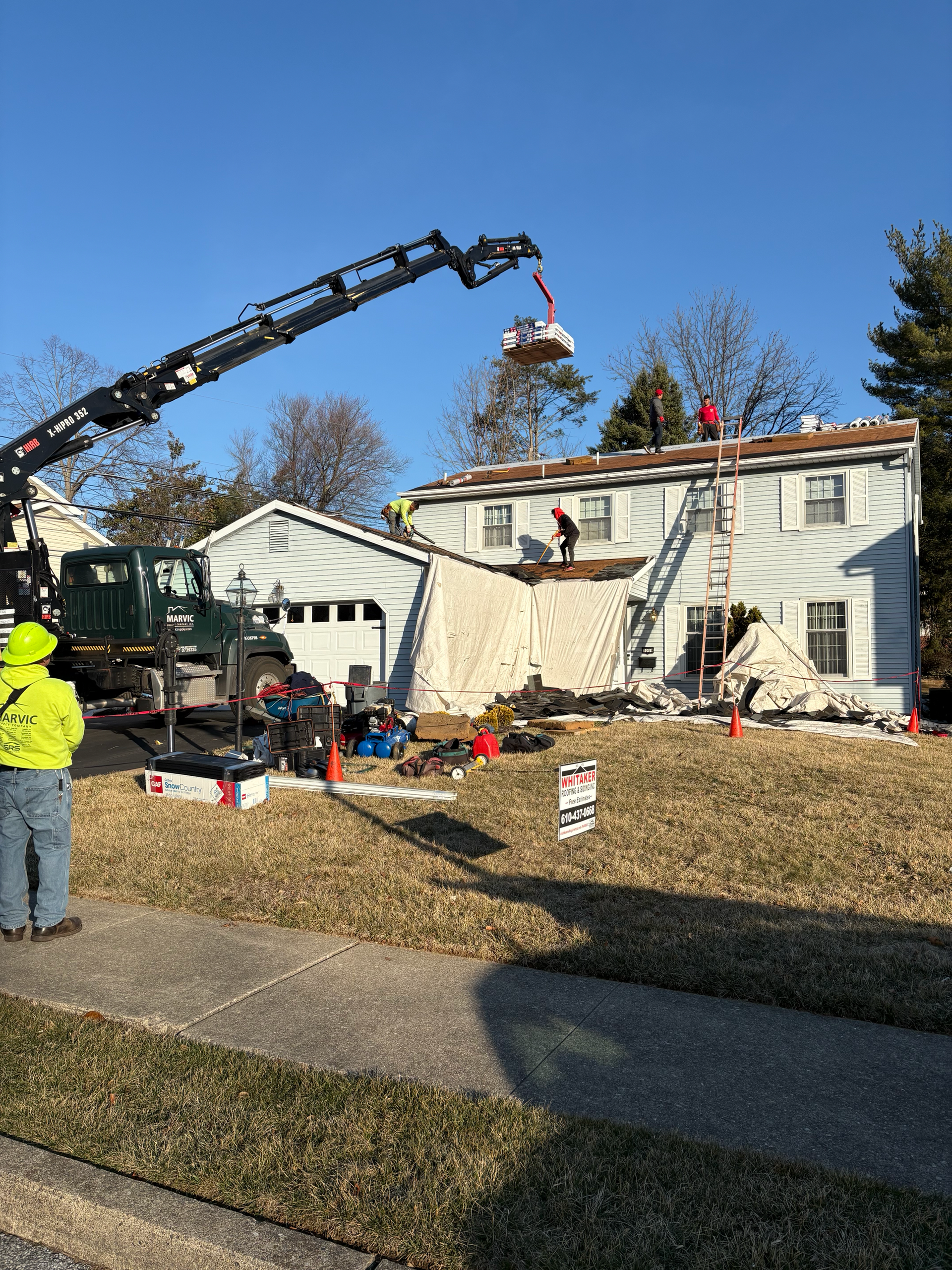 A crane is lifting a tree from the roof of a house.