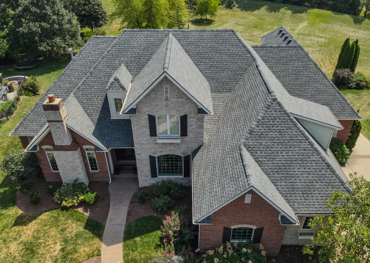 An aerial view of a large brick house with a gray roof.