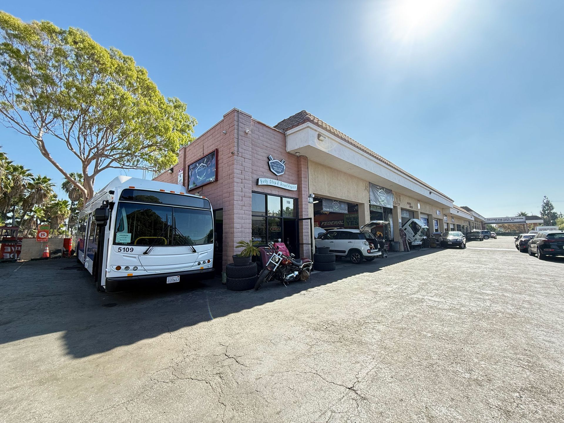 A bus parked outside a brick building with a business front on a sunny day.