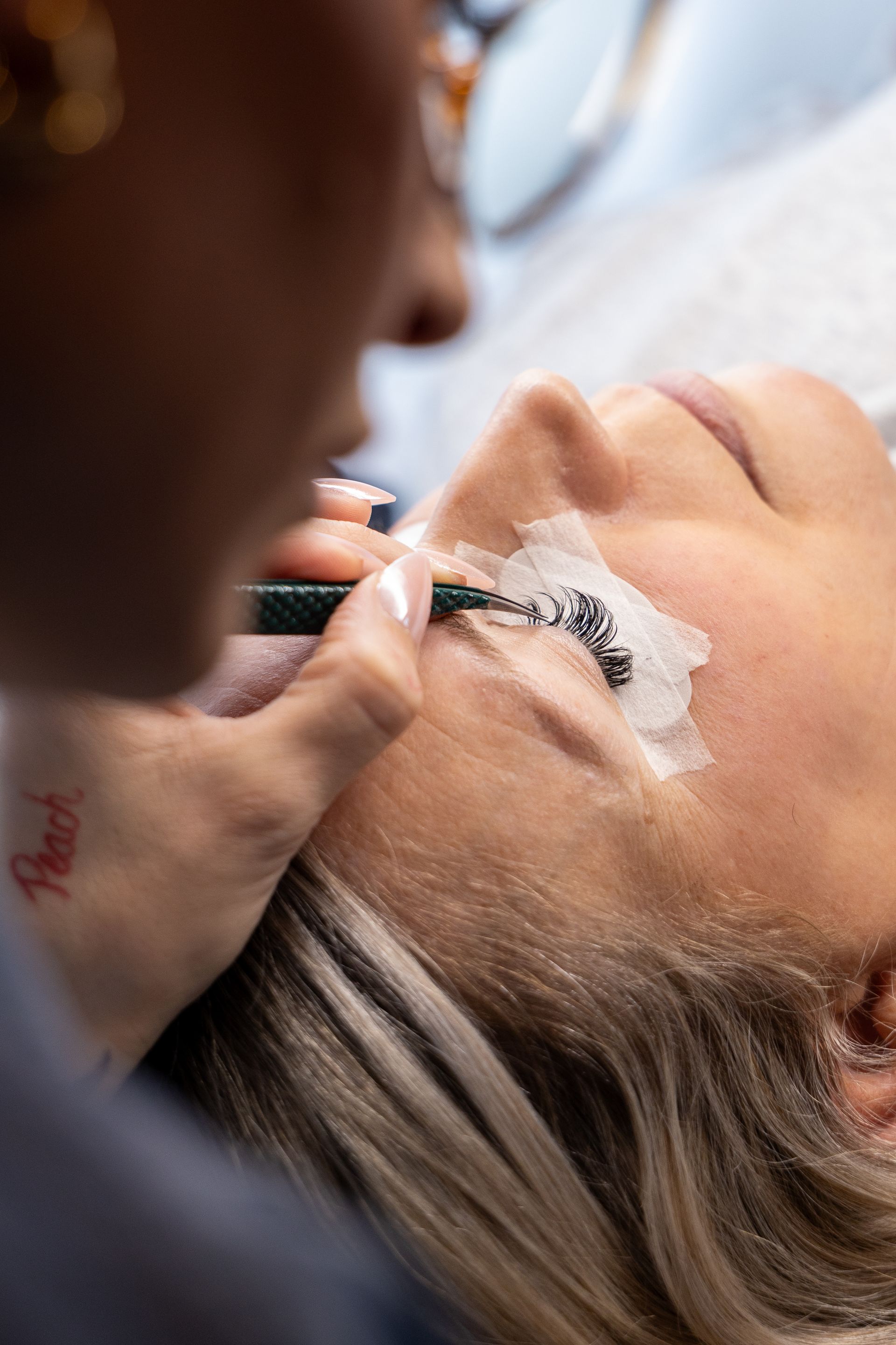 Close-up of a makeup artist applying eye makeup to a client lying down
