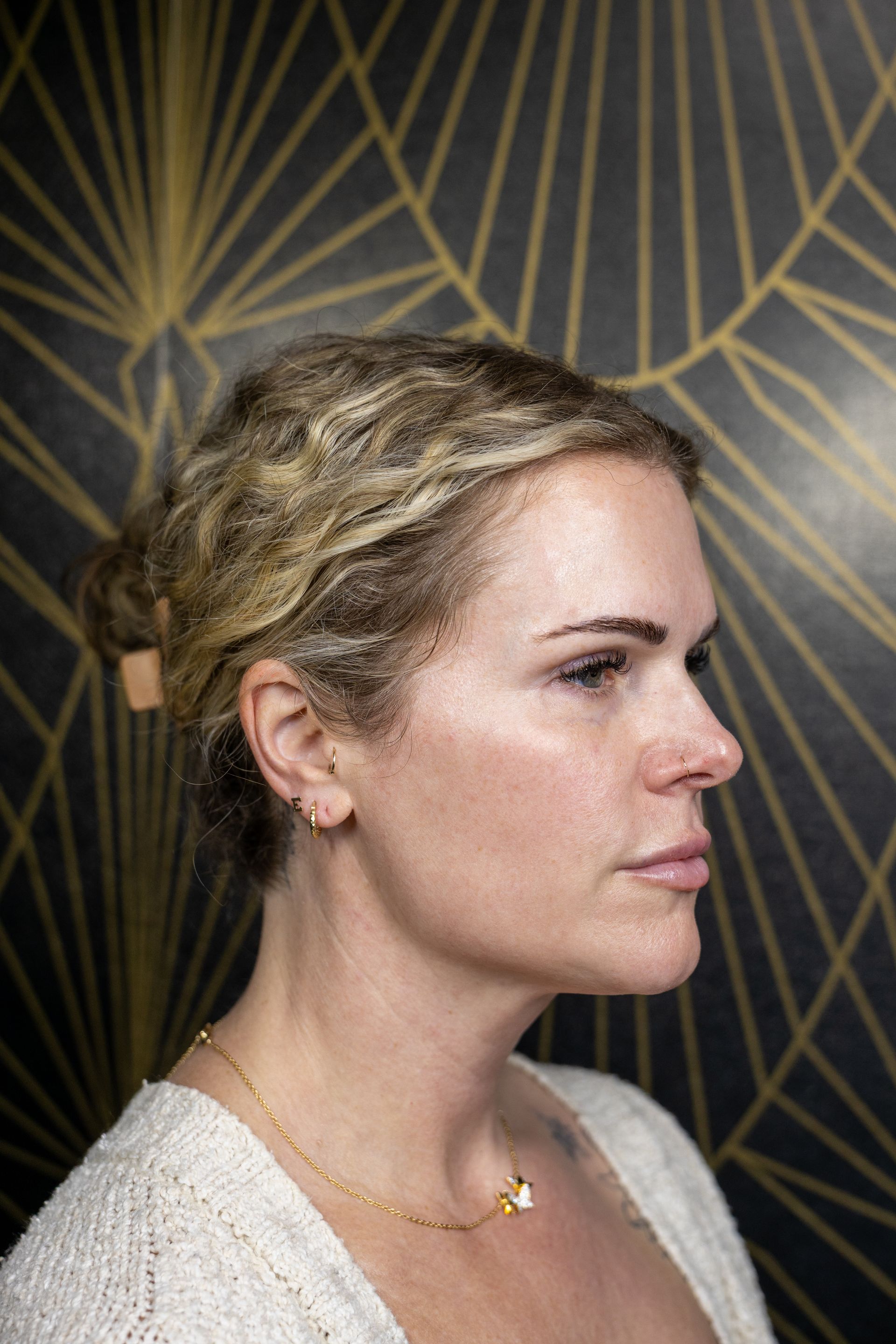 Profile portrait of a woman with braided blonde hair against a dark geometric background