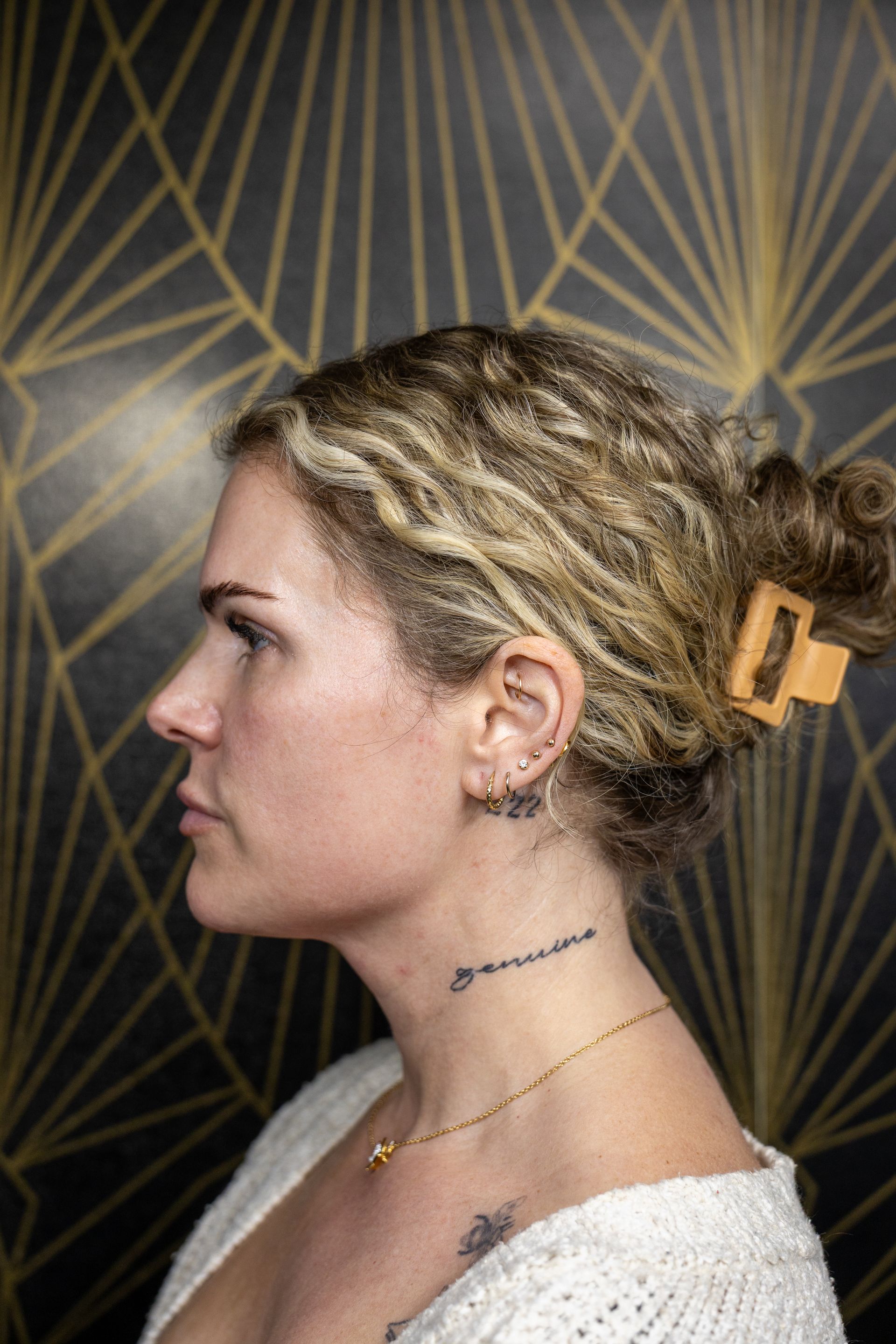 Profile portrait of a woman with a hair clip against a dark geometric patterned background