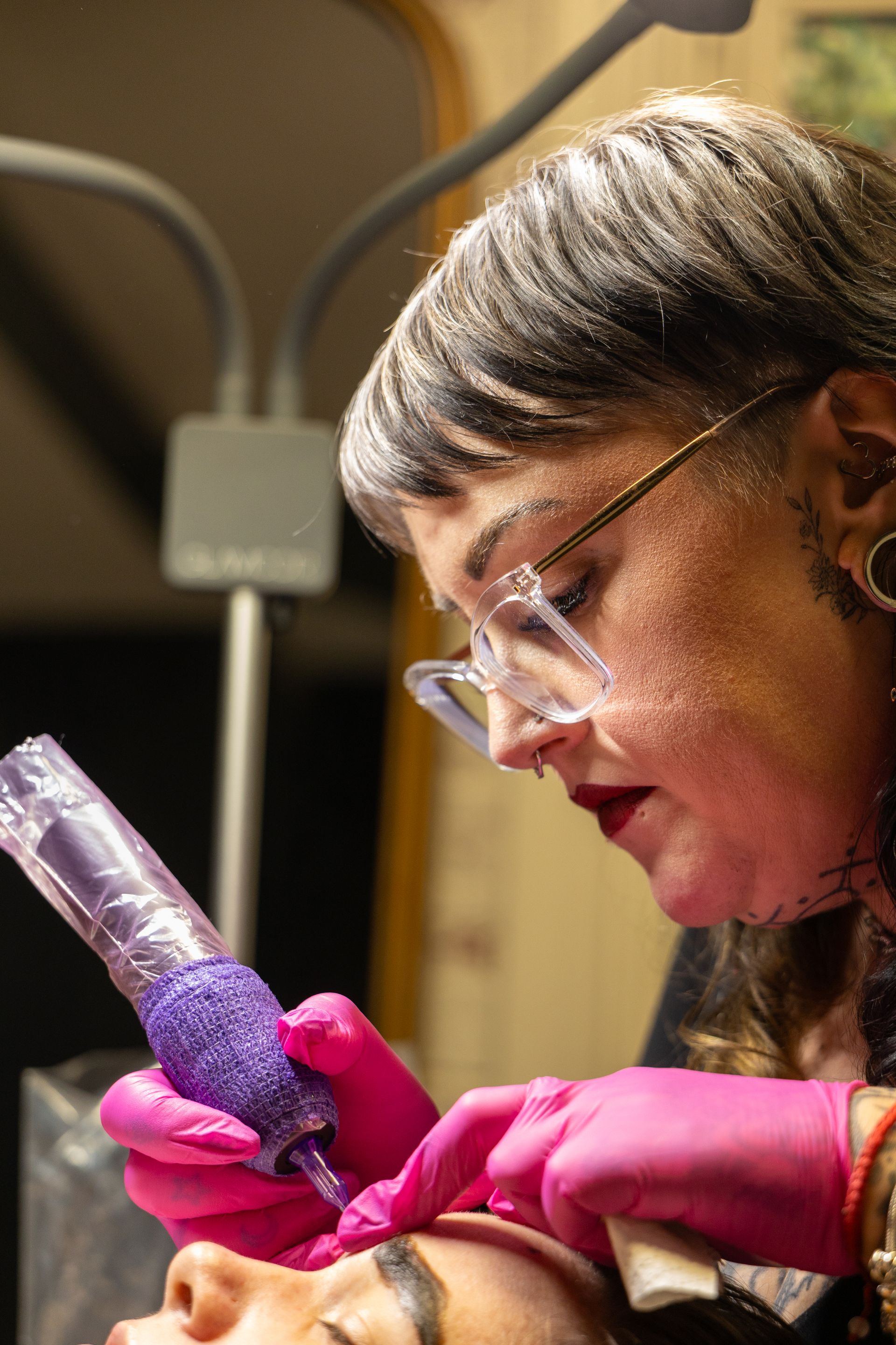 Scientist in pink gloves examining a purple sample in a lab