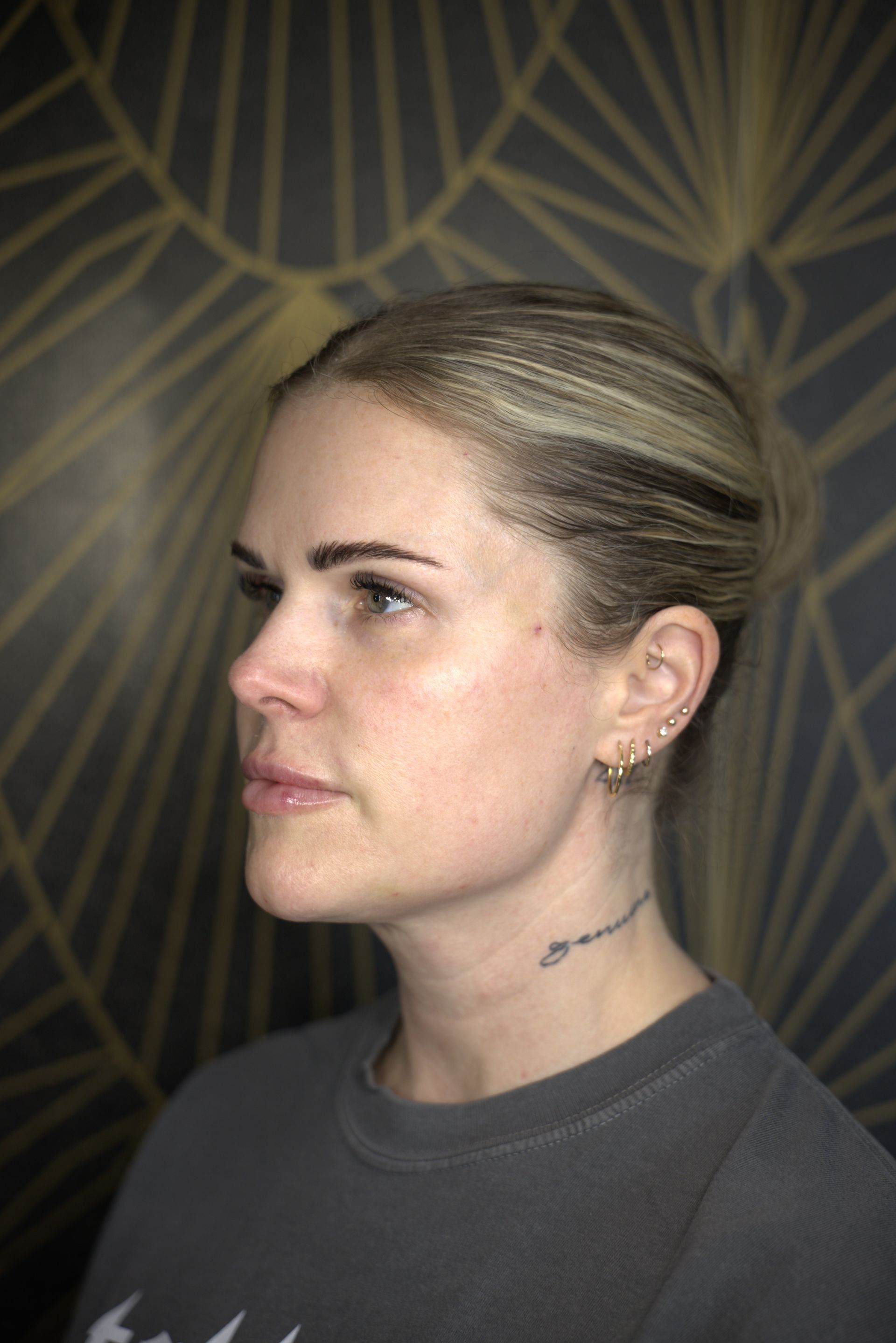 Profile portrait of a person with blonde hair against a dark geometric wallpaper background