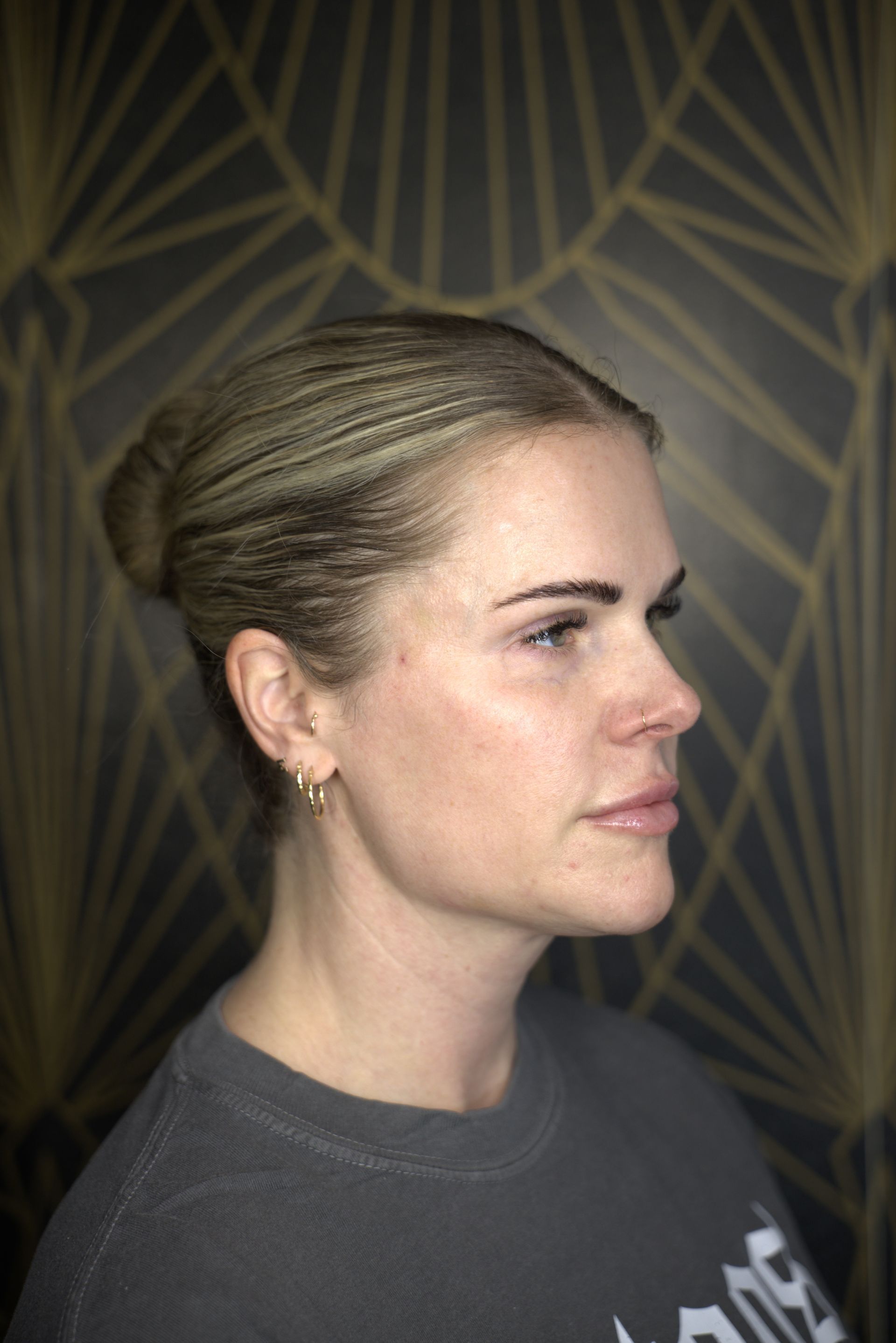 Side-profile portrait of a person with blonde hair against a geometric patterned background