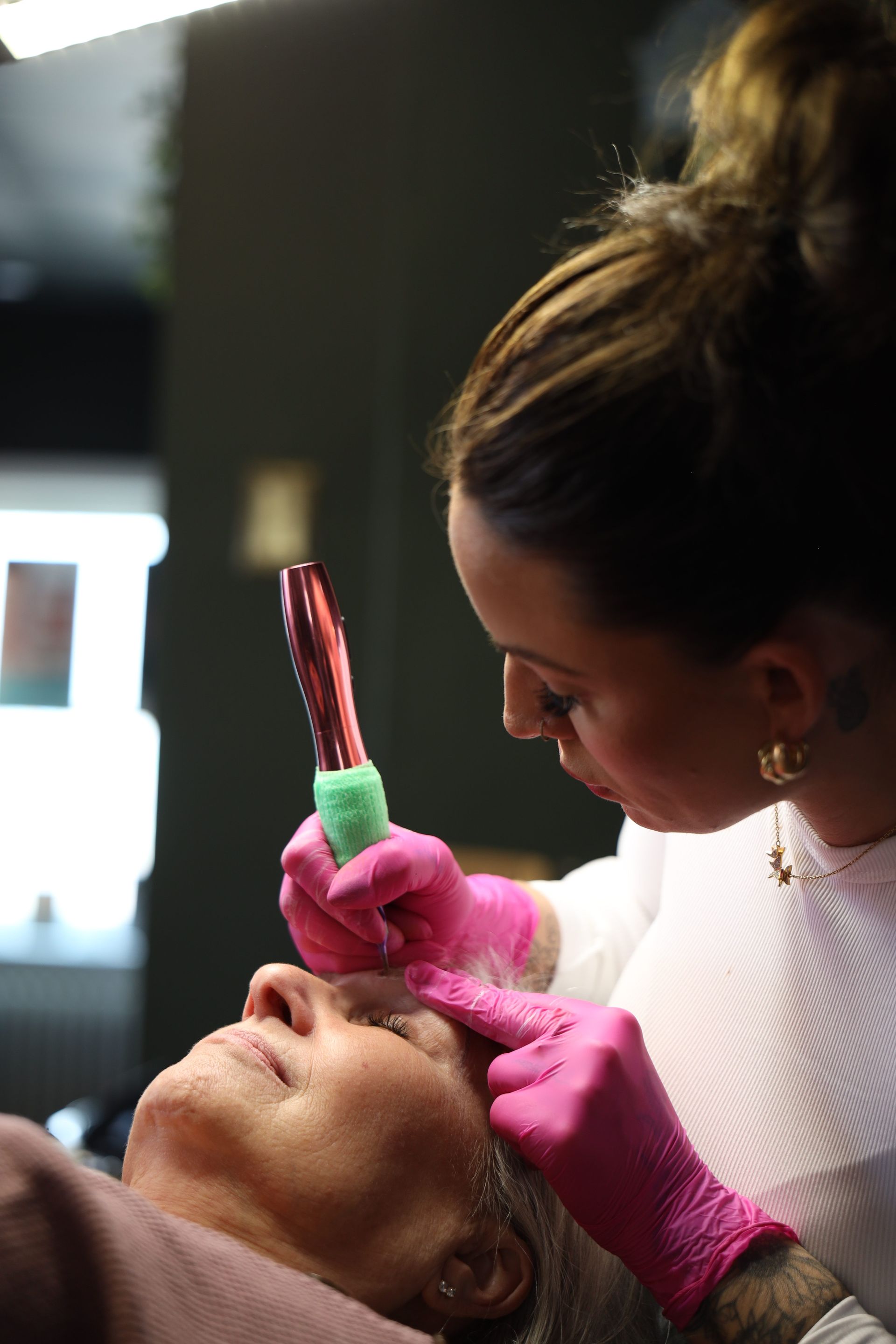 Dentist in pink gloves using a dental tool on a reclining patient during an exam