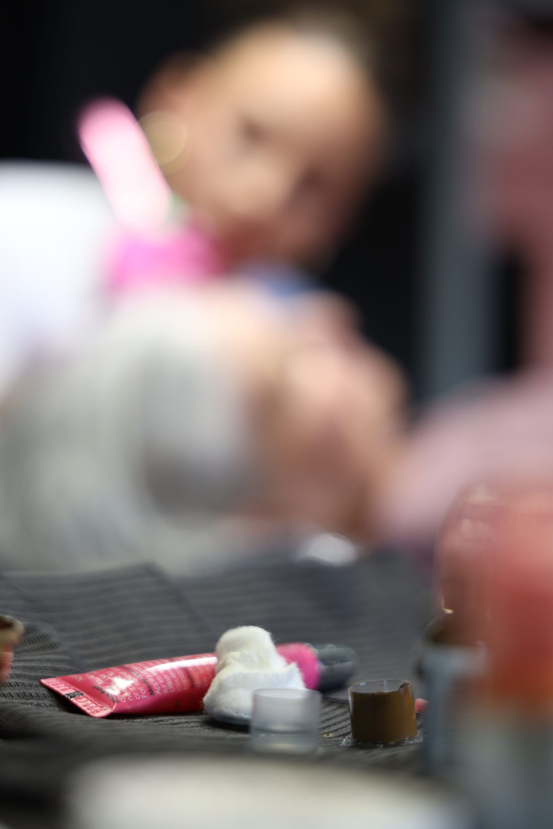 Blurred person holding a pink toothbrush over a table with small objects in the foreground