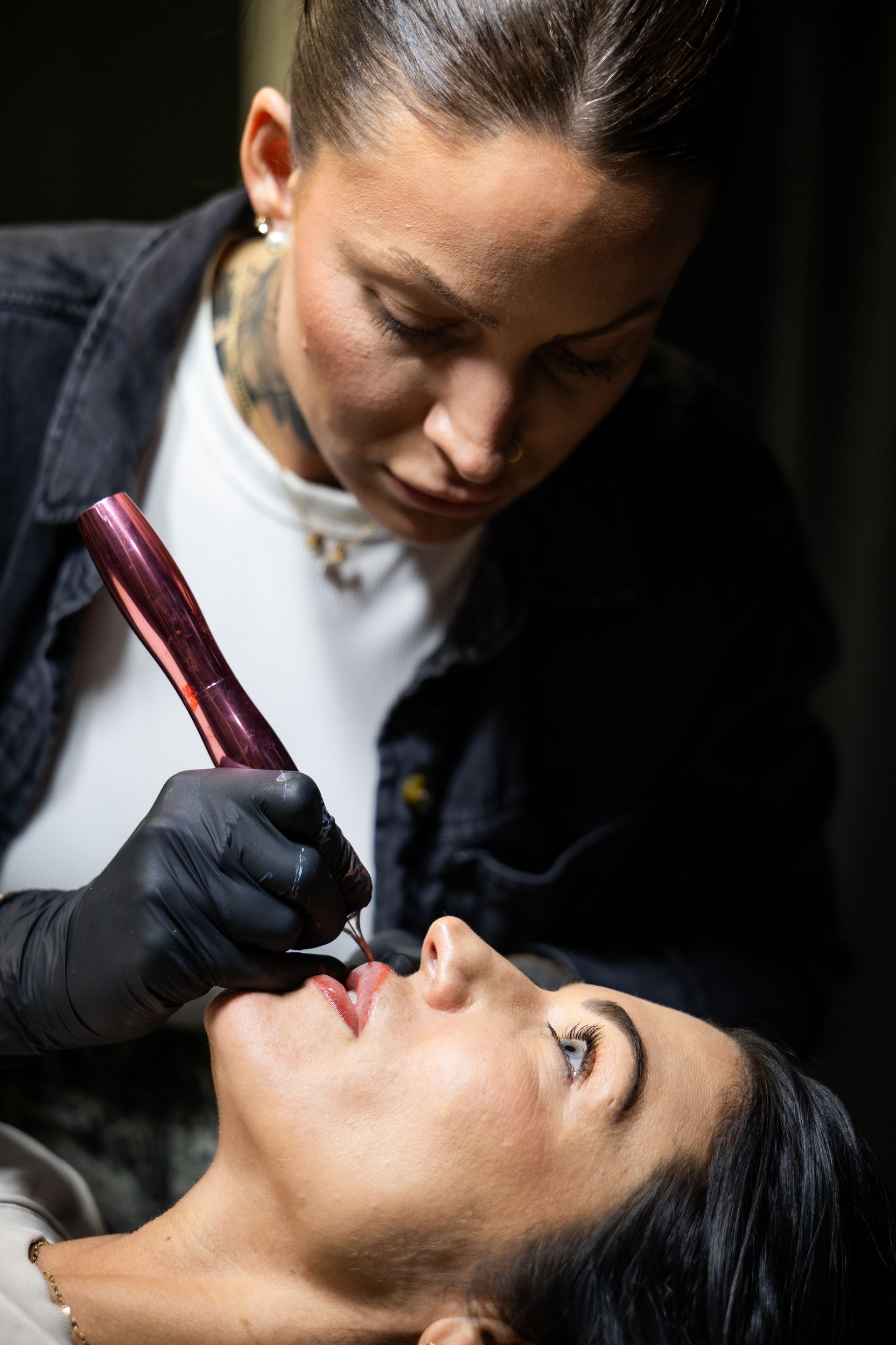 Dentist examining a patient’s mouth with a dental tool in a dimly lit clinic