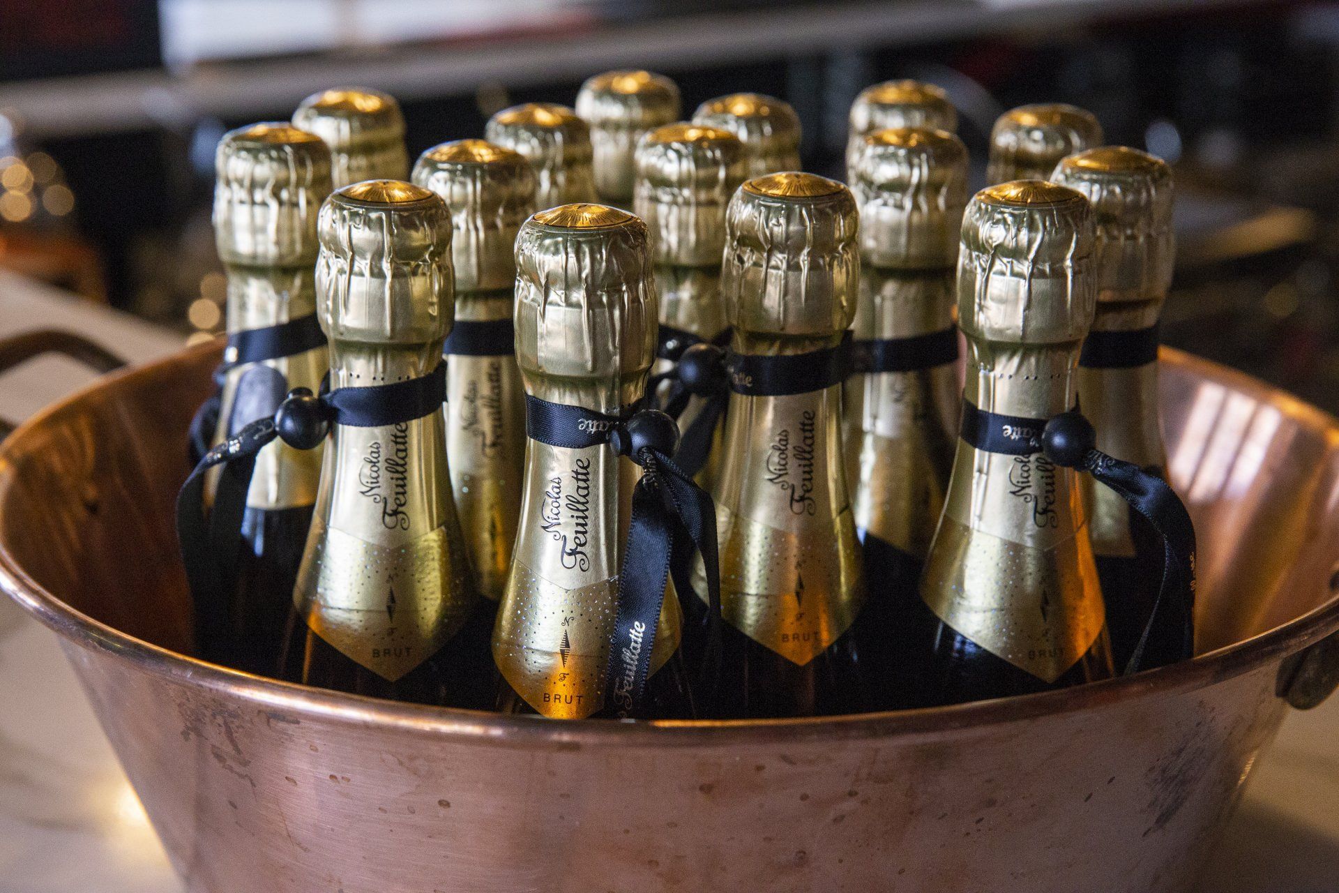 A copper bowl filled with bottles of champagne on a table.