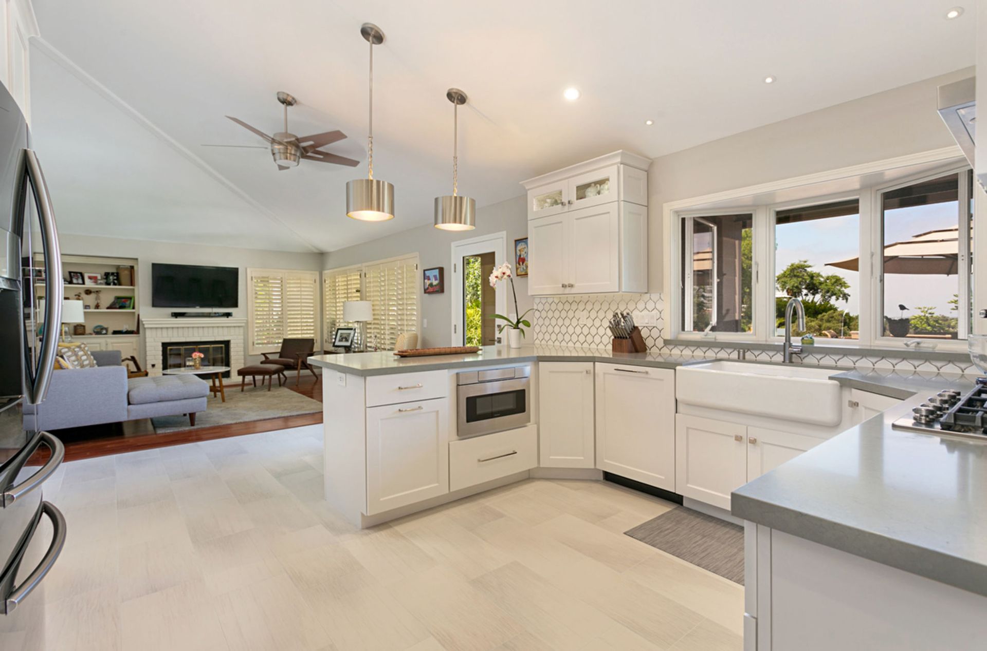 Open-concept kitchen with white cabinets, a light-colored floor, and a view of the living area beyond.