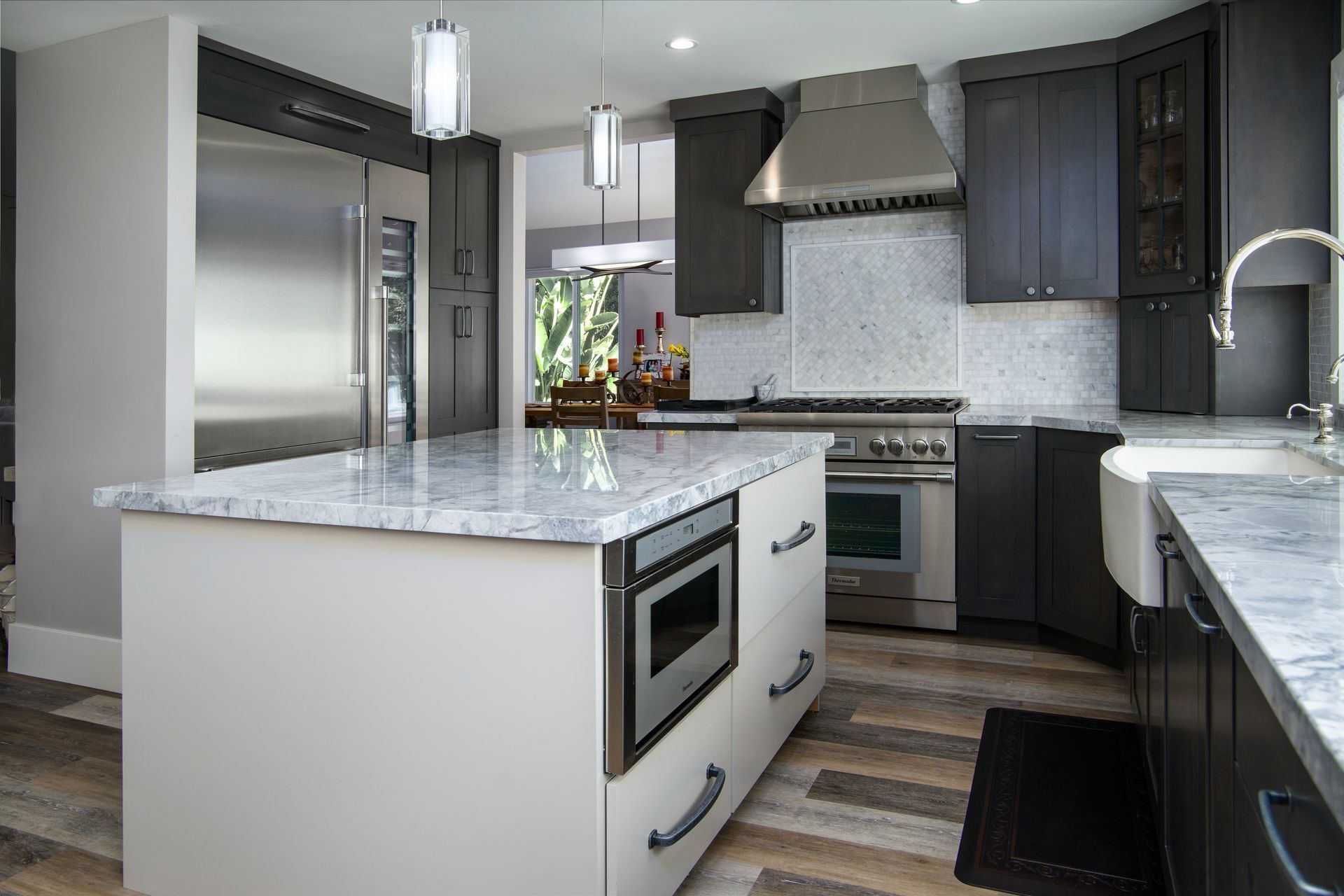 Modern kitchen with gray and white cabinets, stainless steel appliances, and a marble countertop island.